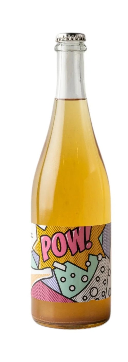 A glass bottle filled with yellow-colored beverage, featuring a pop art style label with the word "POW!" in pink letters and comic book design elements.