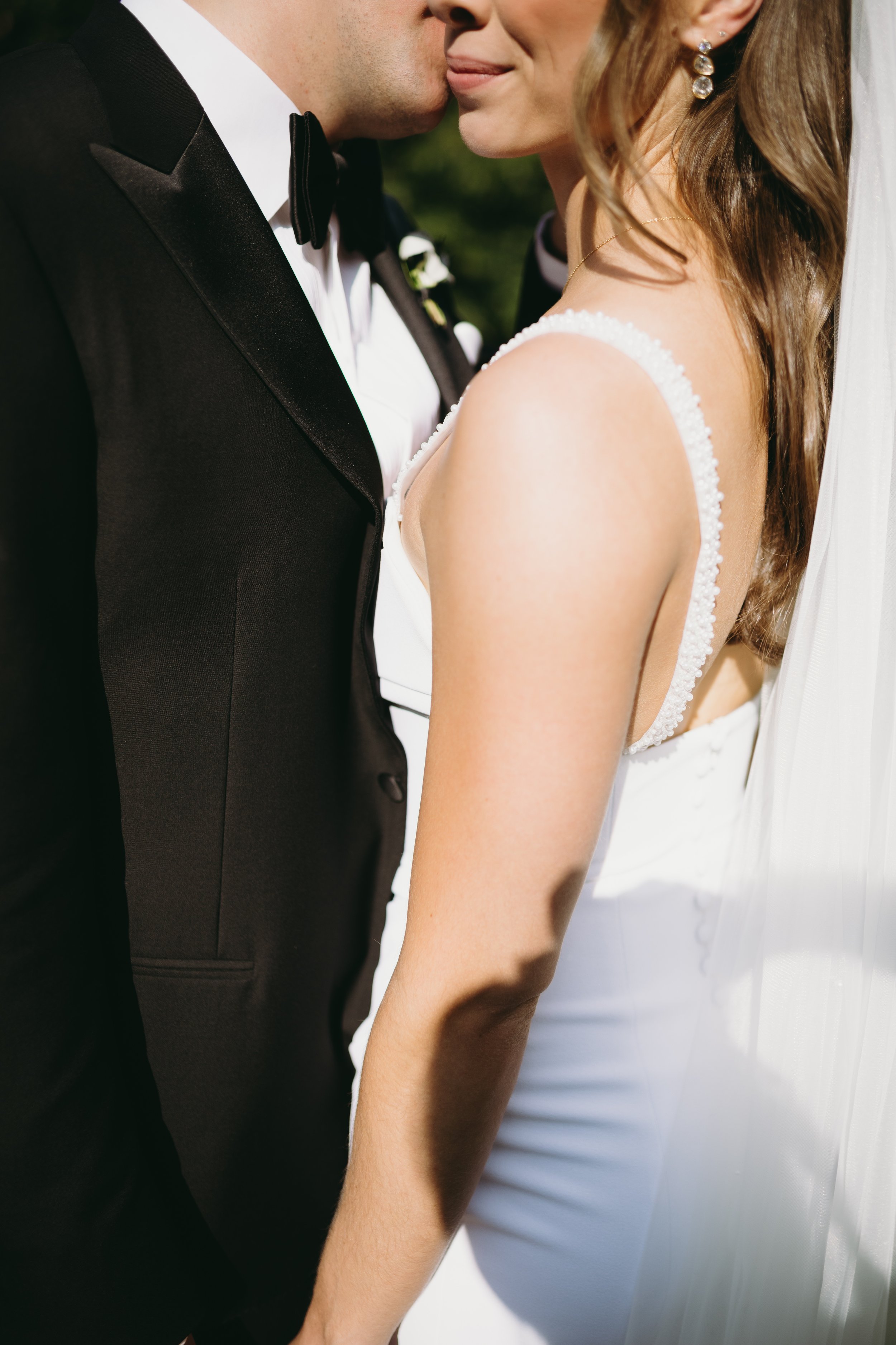 A bride and groom sharing an intimate moment, with the groom kissing the bride's cheek during their wedding.