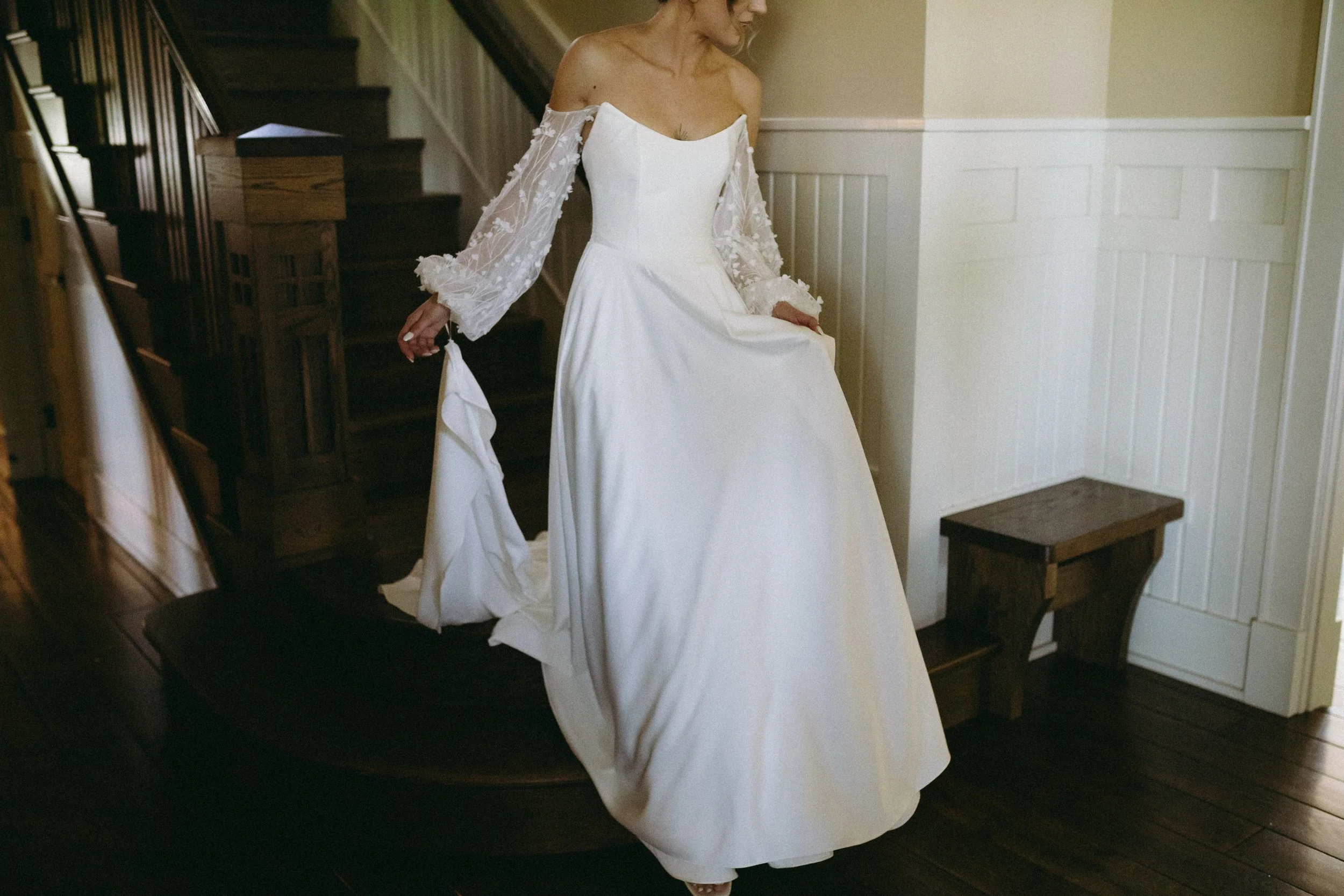 A bride in a white wedding dress walking down stairs.