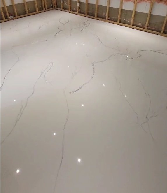 Piso de baldosas blancas con vetas grises en una sala en construcción.