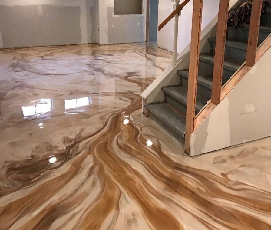 Suelos de mármol con patrones en tonos marrones, beige y crema, en una interior con escaleras de madera y peldaños grises.