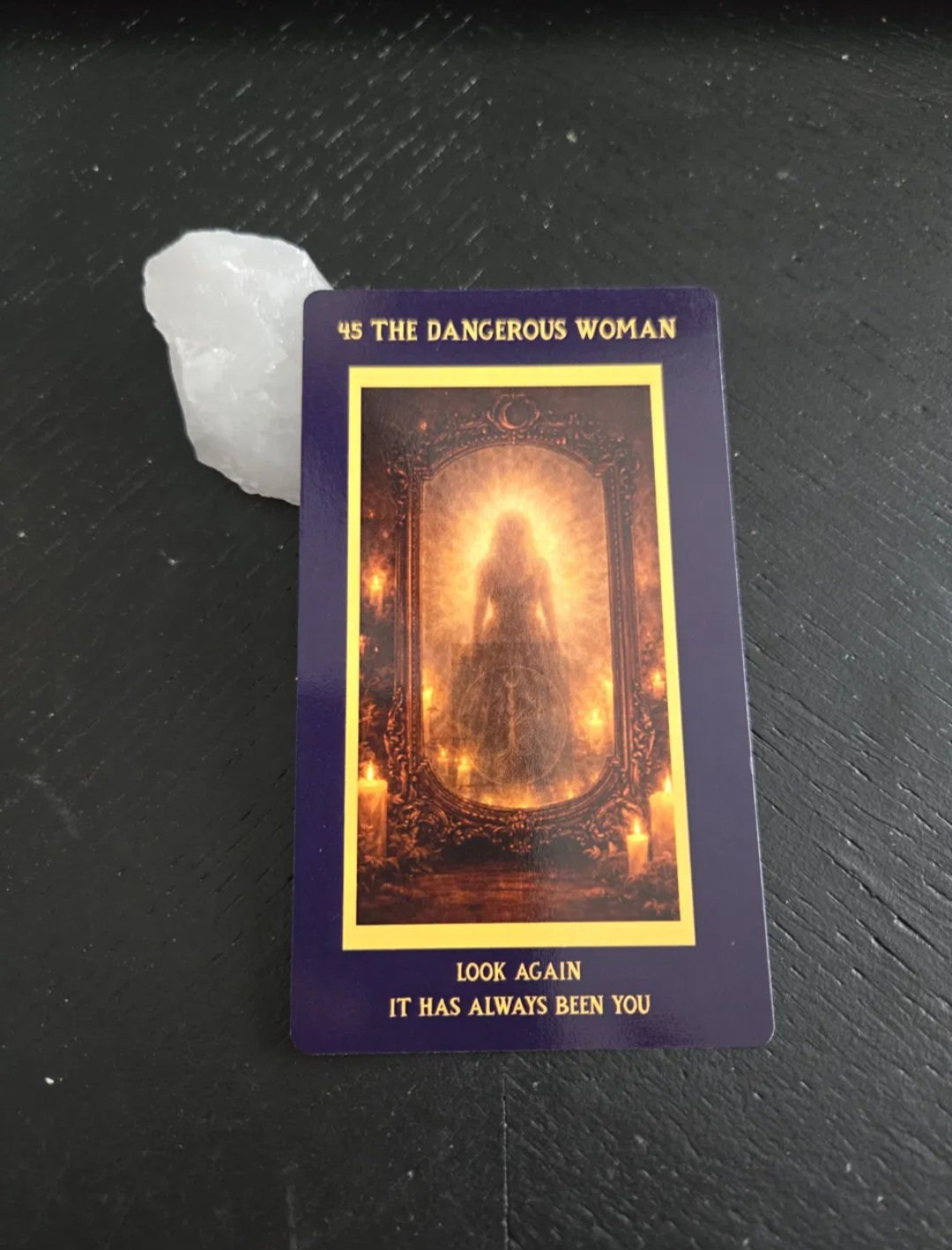 A tarot card titled "45 The Dangerous Woman" showing a silhouette of a woman surrounded by a glowing aura and candles in a ornate frame. Text at the bottom reads "Look Again, It Has Always Been You".
