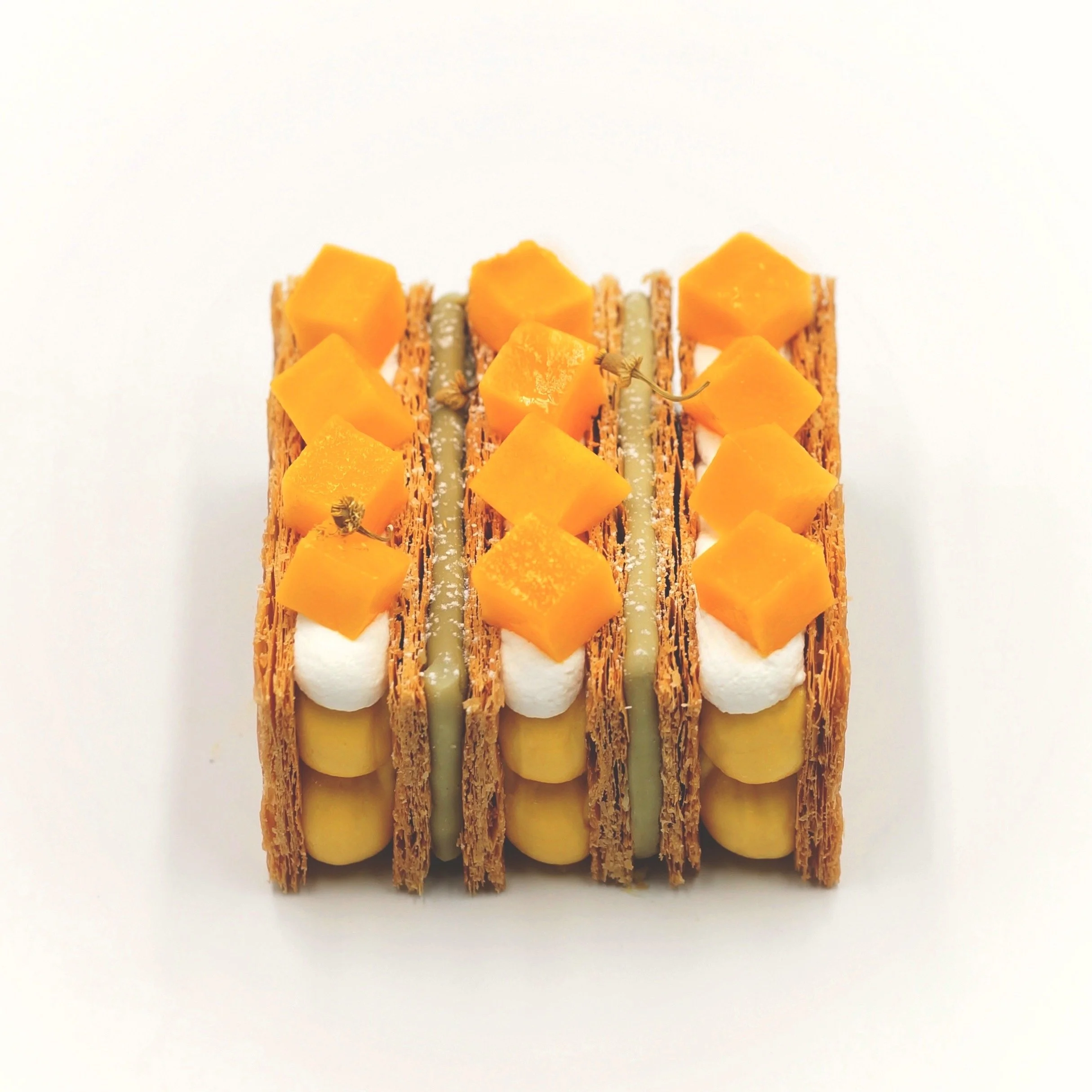 Mille feuille with fresh mango pieces, whipped cream, and pastry cream on a white background