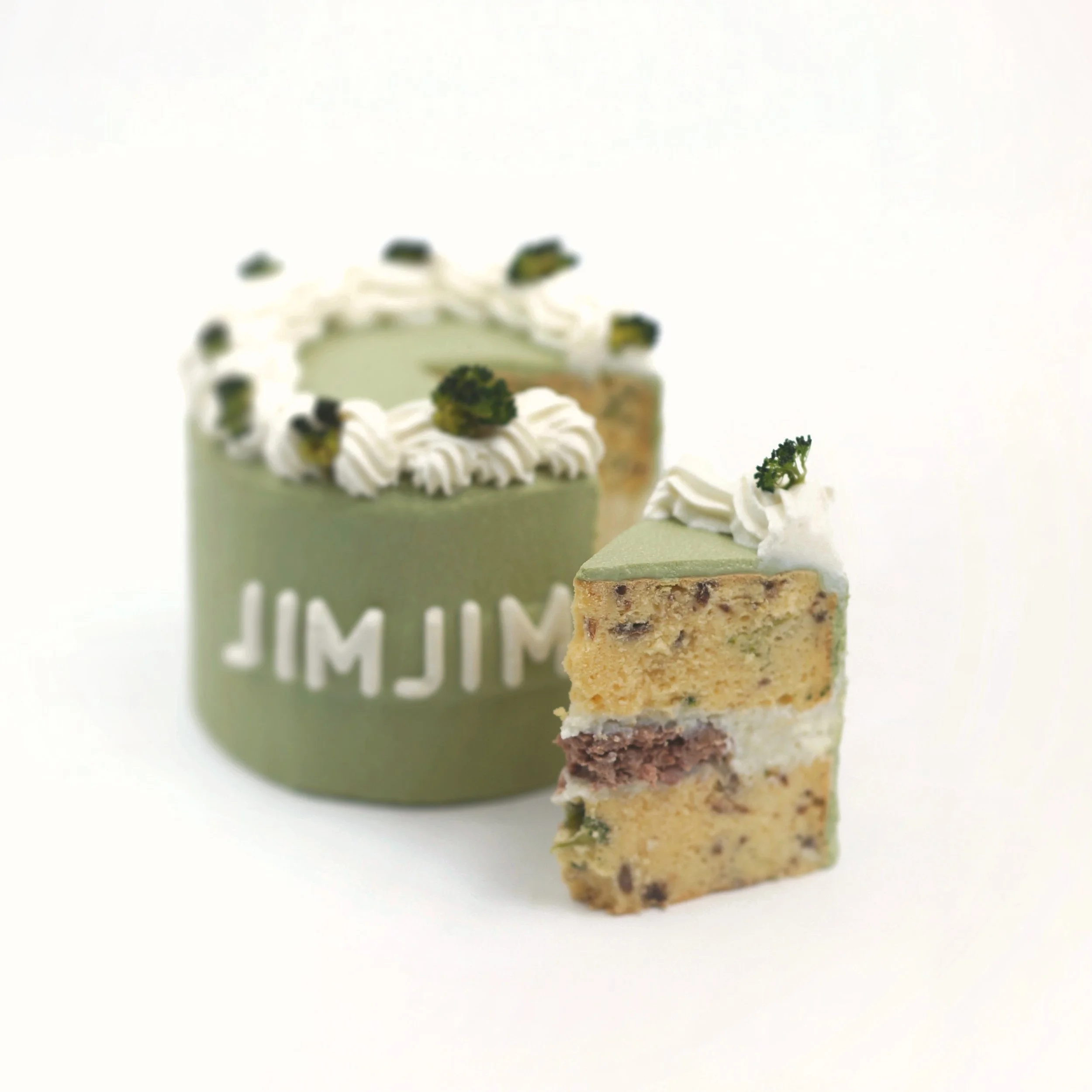A small slice of layered pet cake cut out from a pastel green cake with white frosting and green garnish