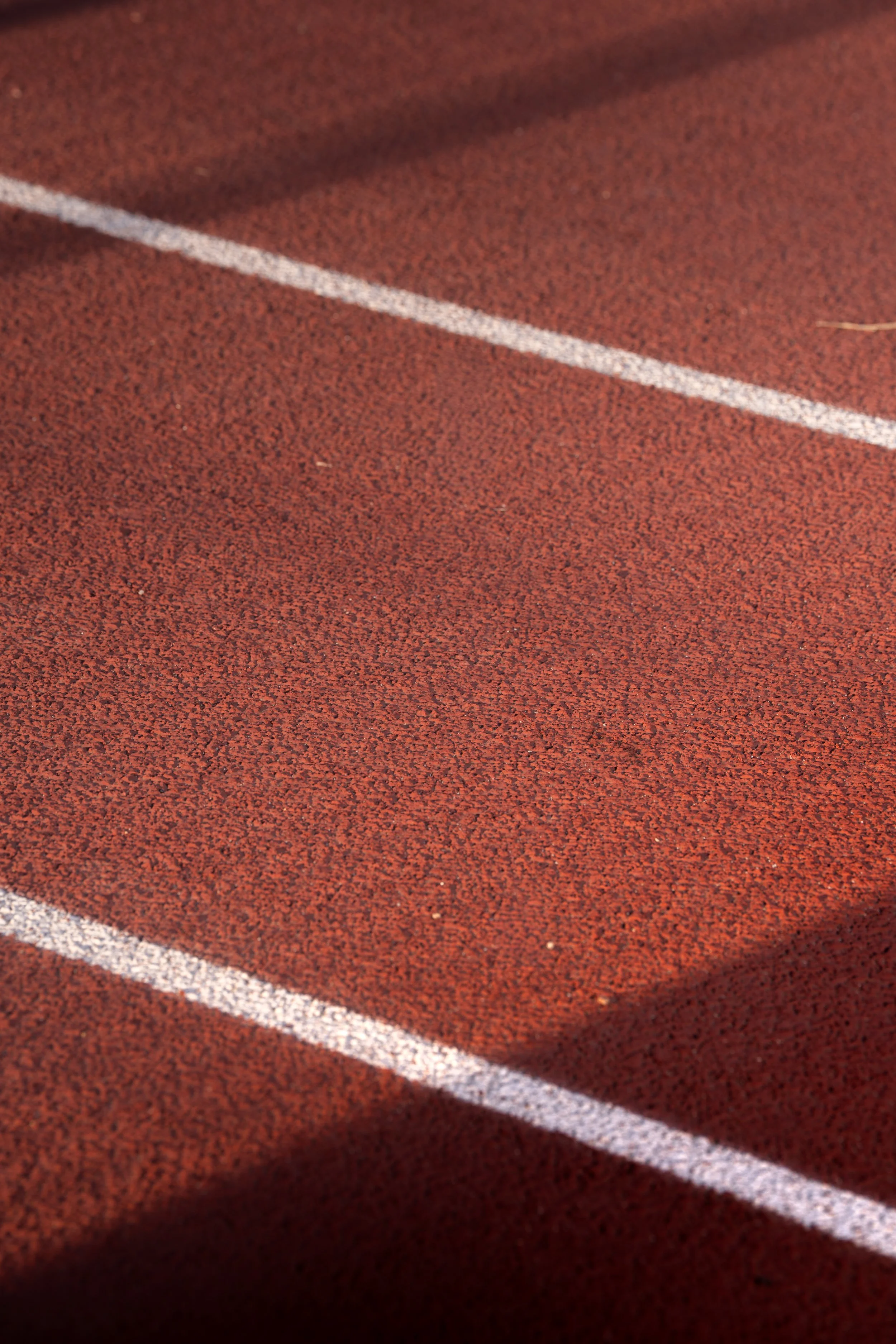 Close-up of a red running track with white lane markings.