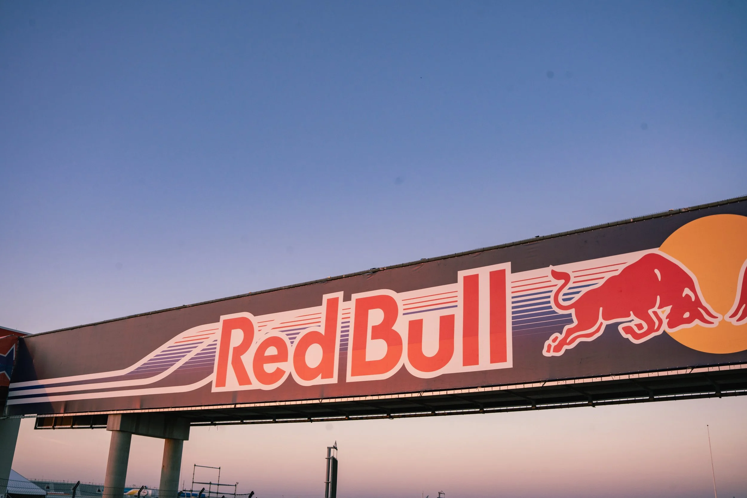 Red Bull logo on a billboard against a sky at dusk.