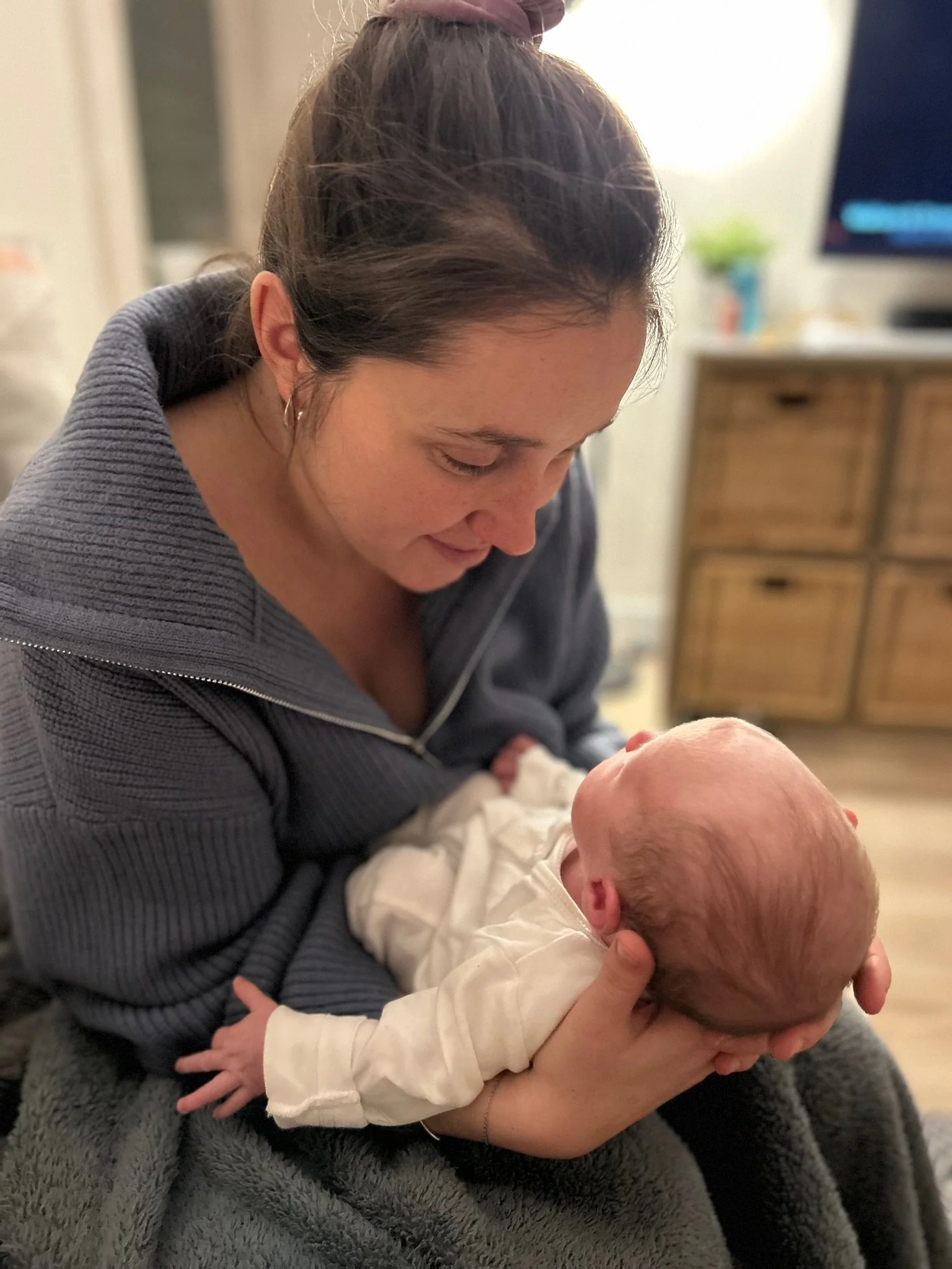 Alice holding her daughter facing her on her lap with a blanket wrapped over her knees.