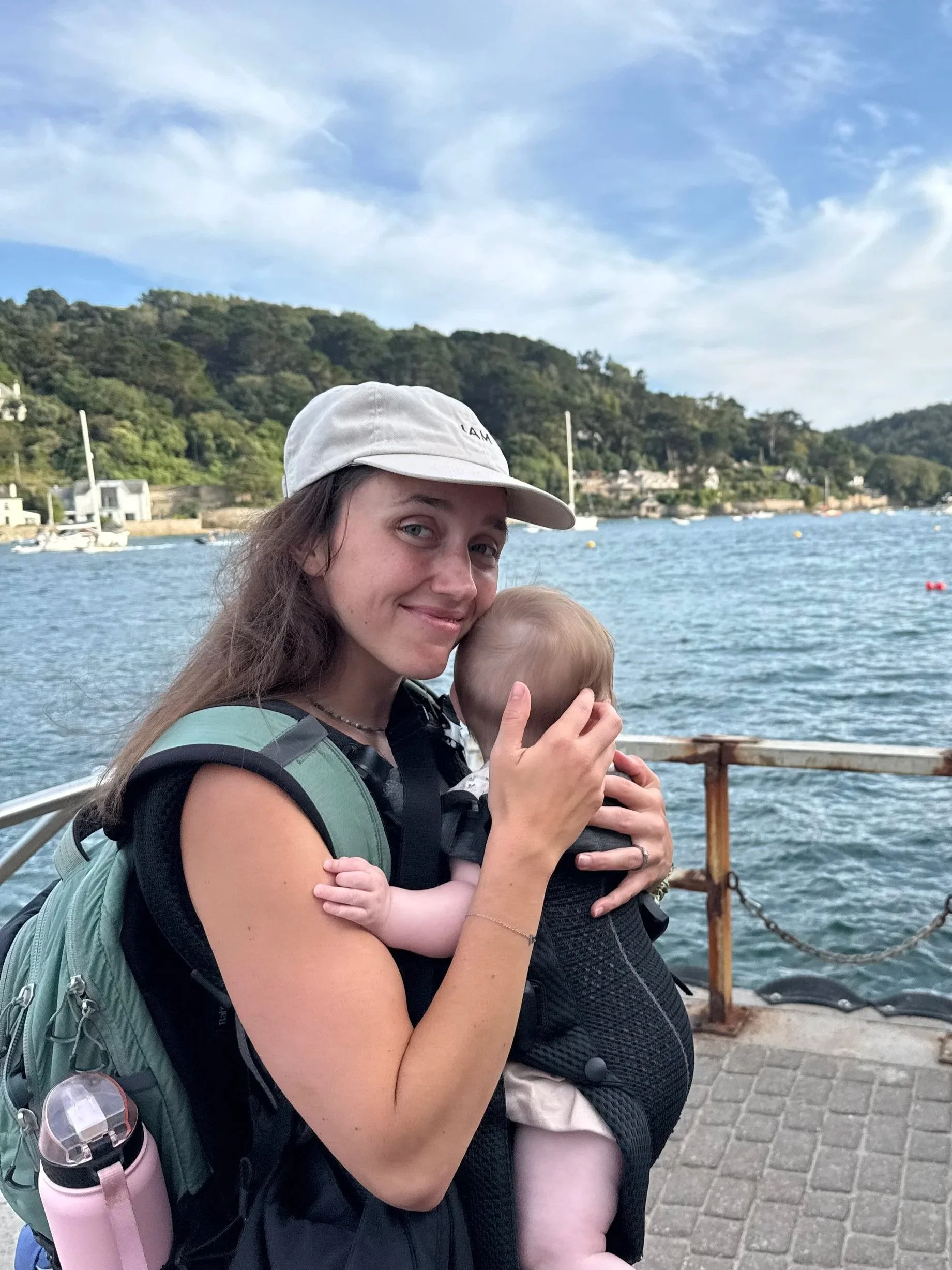 Alice holding her daughter in front of the sea in South Devon.
