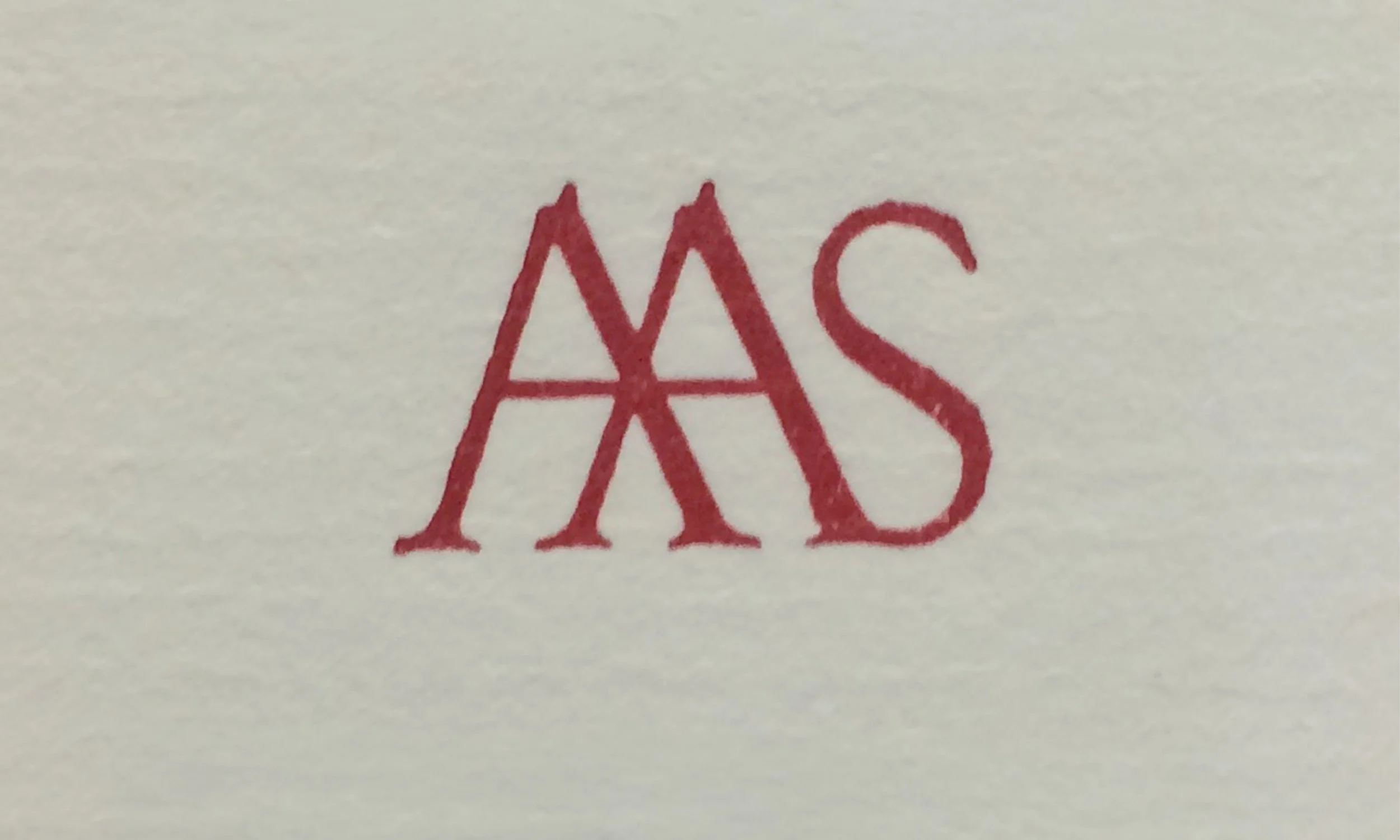 Close-up of a handwritten word 'AAS' in red ink on white paper.
