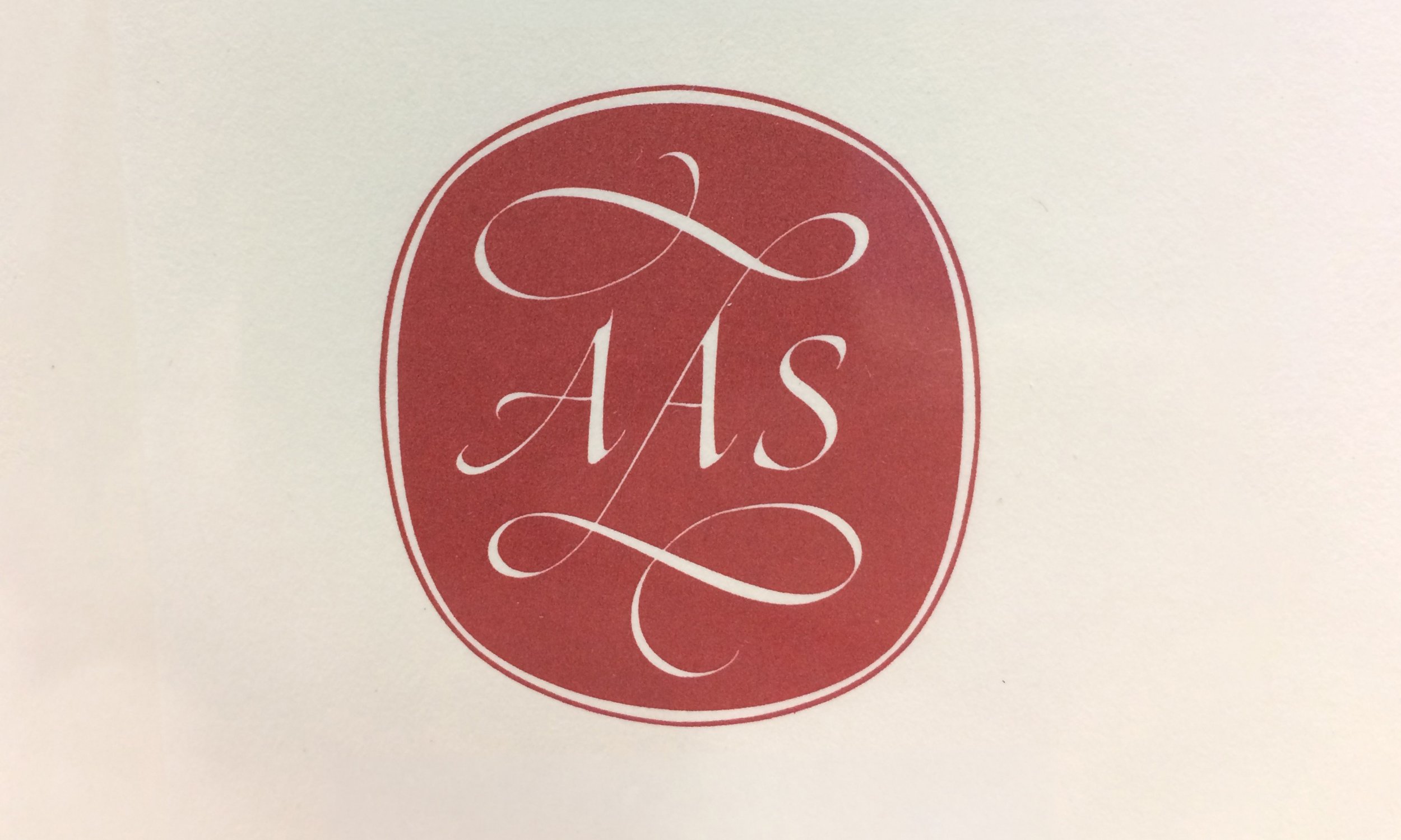 A white background with a red circular emblem containing white cursive text.
