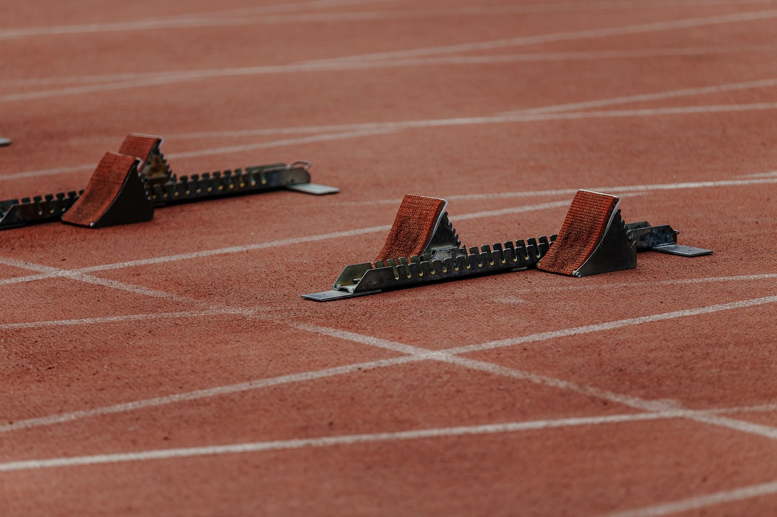 Starting blocks positioned in adjacent lanes on an empty red running track.