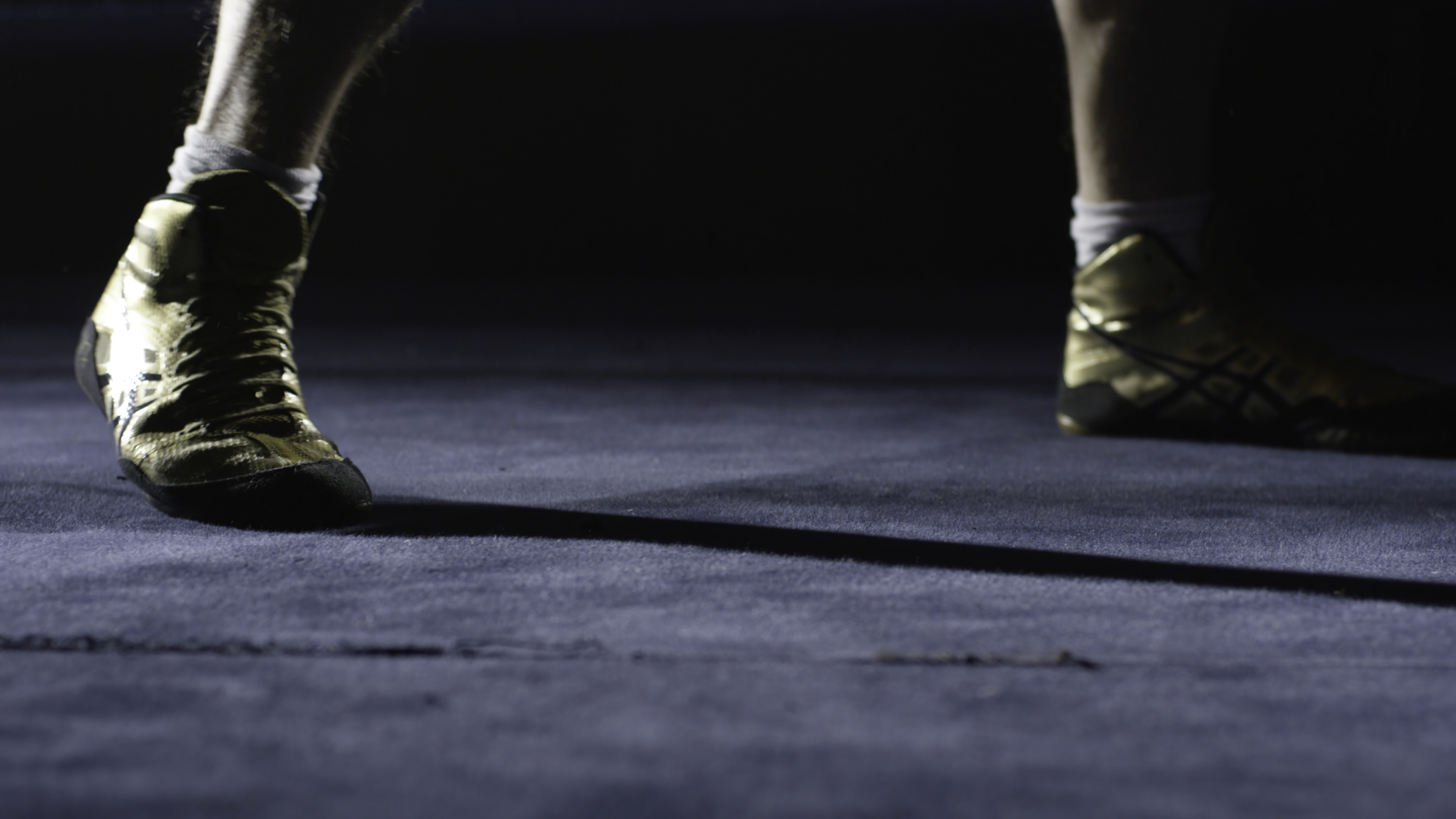 Wrestling shoes on a blue mat.