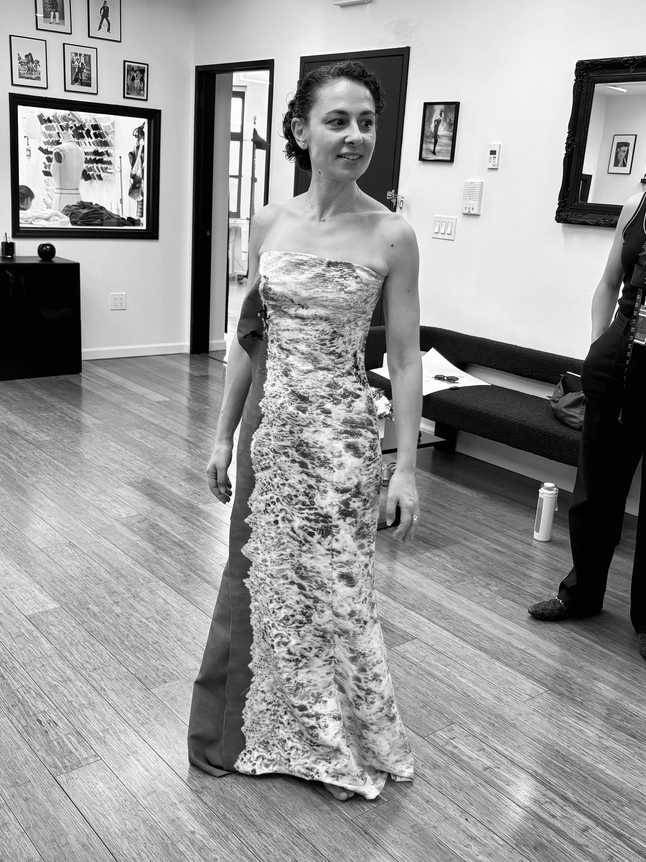 Nicky Conti during a fitting, smiling and turning to view the Memoria dress in the mirror