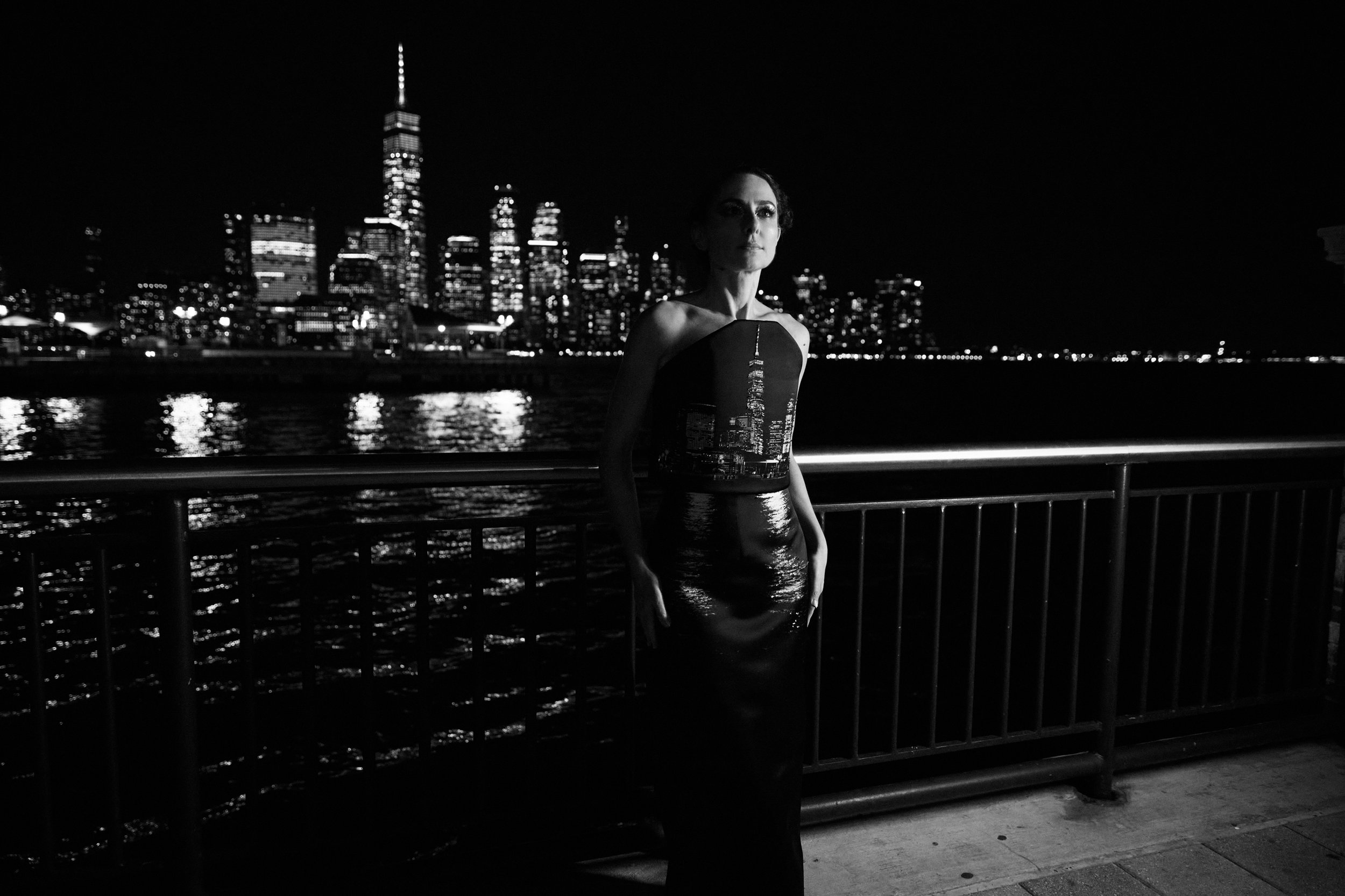 Nicky Conti wearing the Dazziliance couture look on location with the New York City skyline, featuring a structured top printed with the skyline and a skirt printed with water reflections, enhanced by bead embroidery