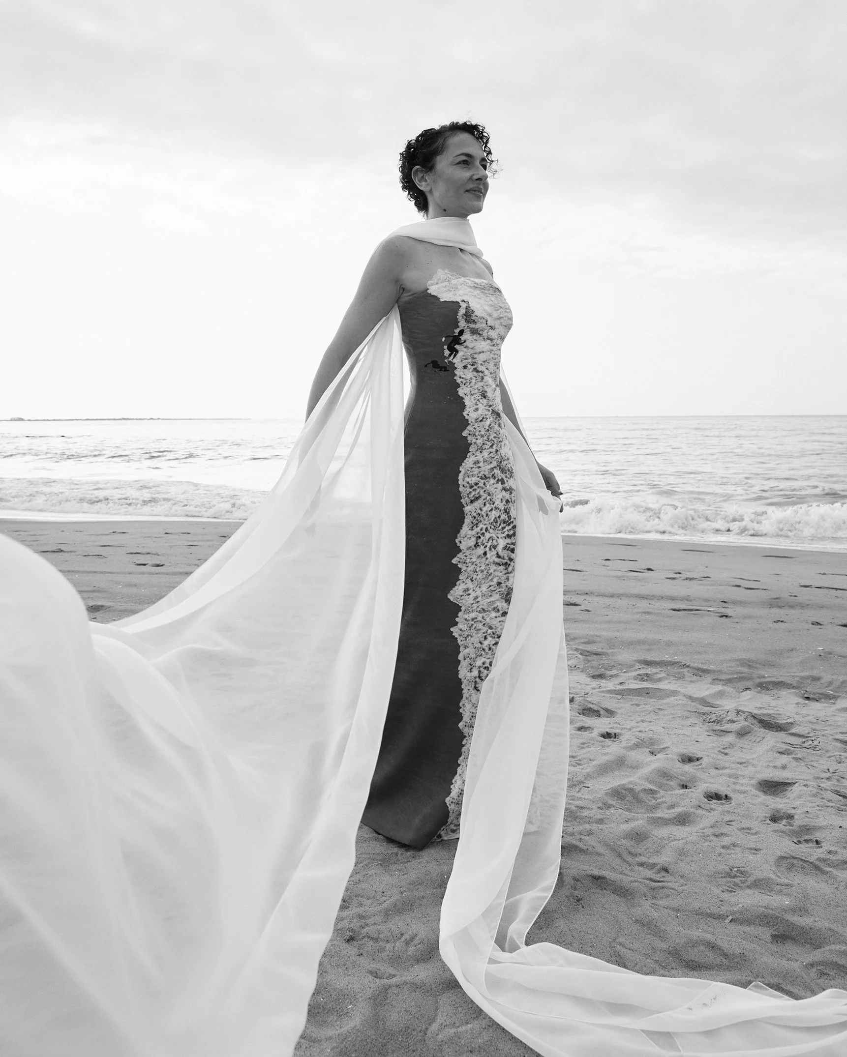 Nicky Conti wearing the Memoria couture dress featuring a shoreline print, photographed on Coney Island Beach in New York City
