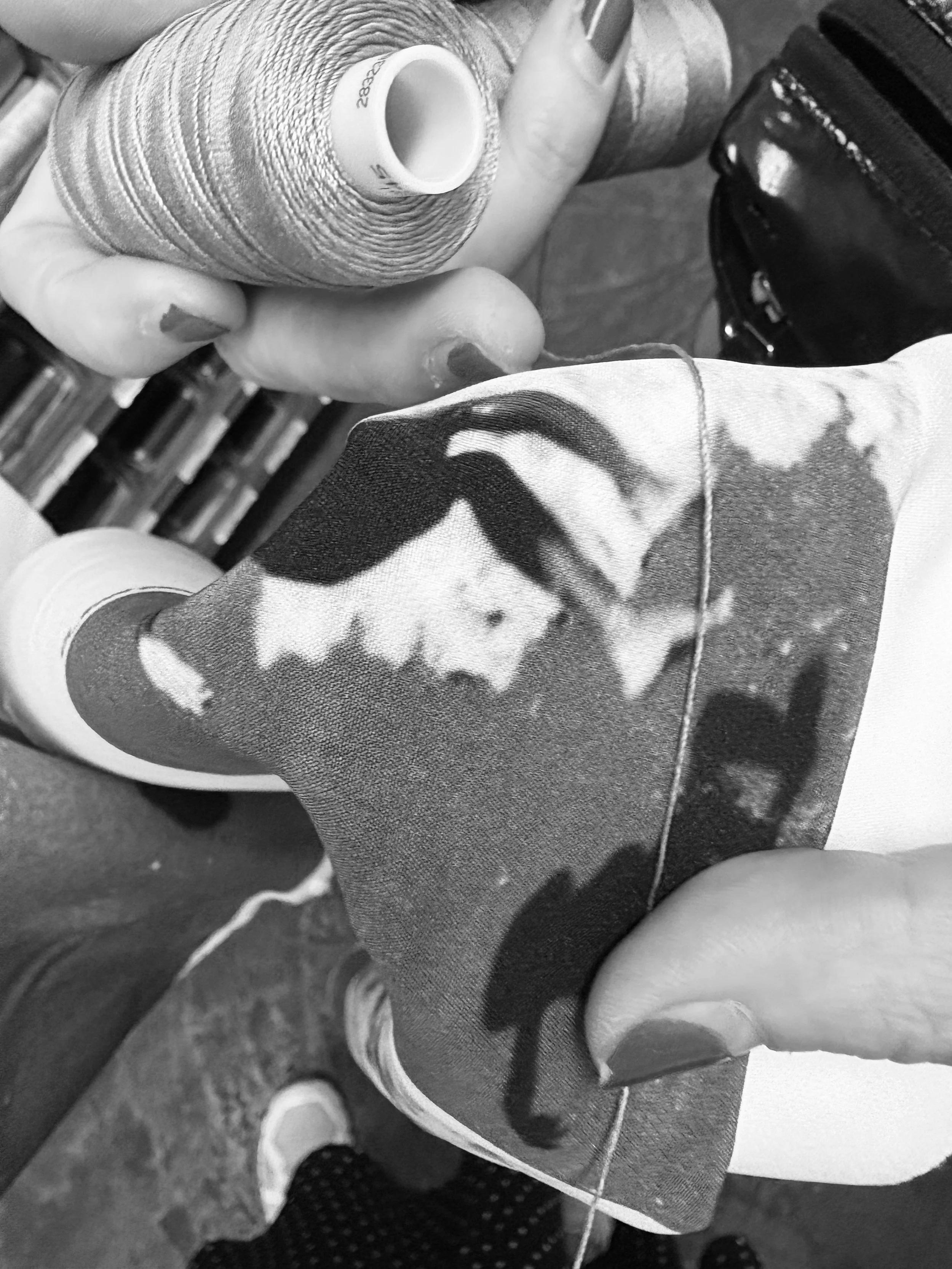 Sarah Esmoingt selecting thread colors using a sample print of the shoreline photograph on poly crepe fabric for the Memoria dress
