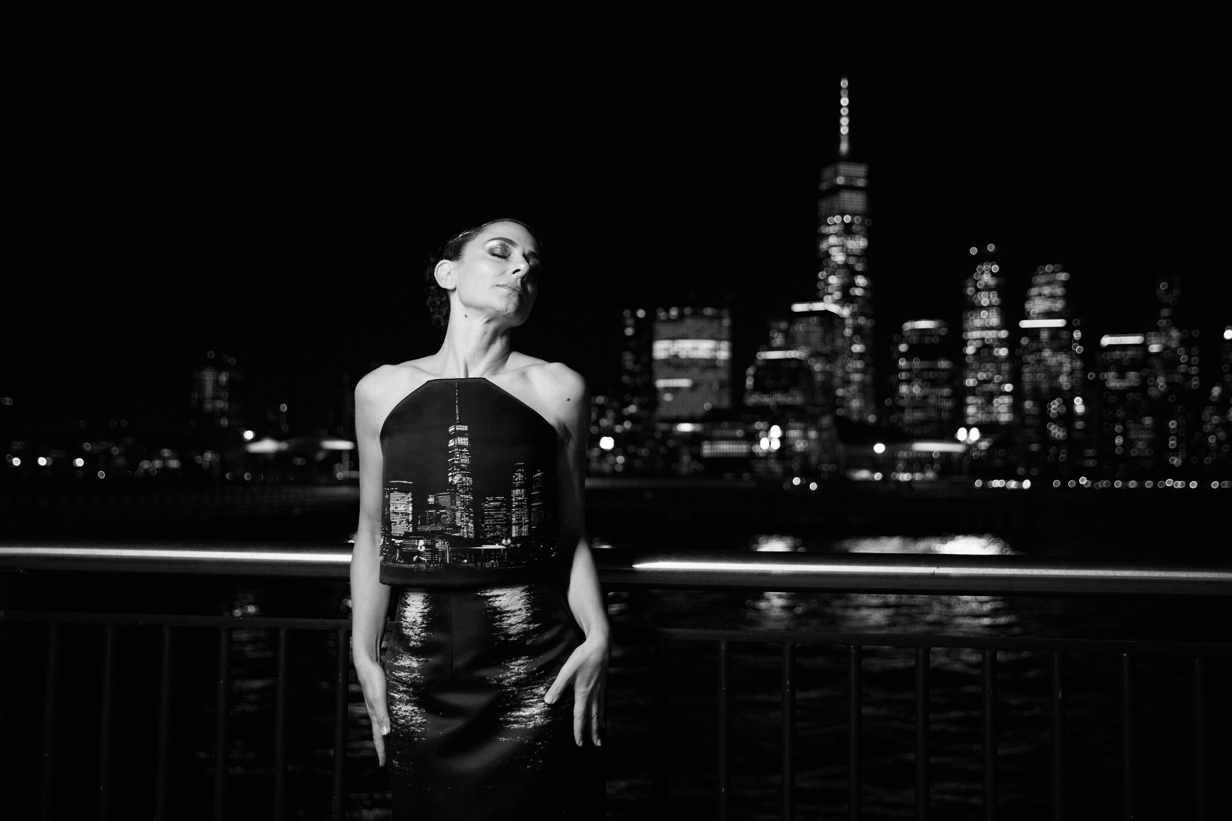 Nicky Conti in the Dazziliance look with bead embroidery accentuating the reflections of city lights on water, photographed with the Manhattan skyline in the background