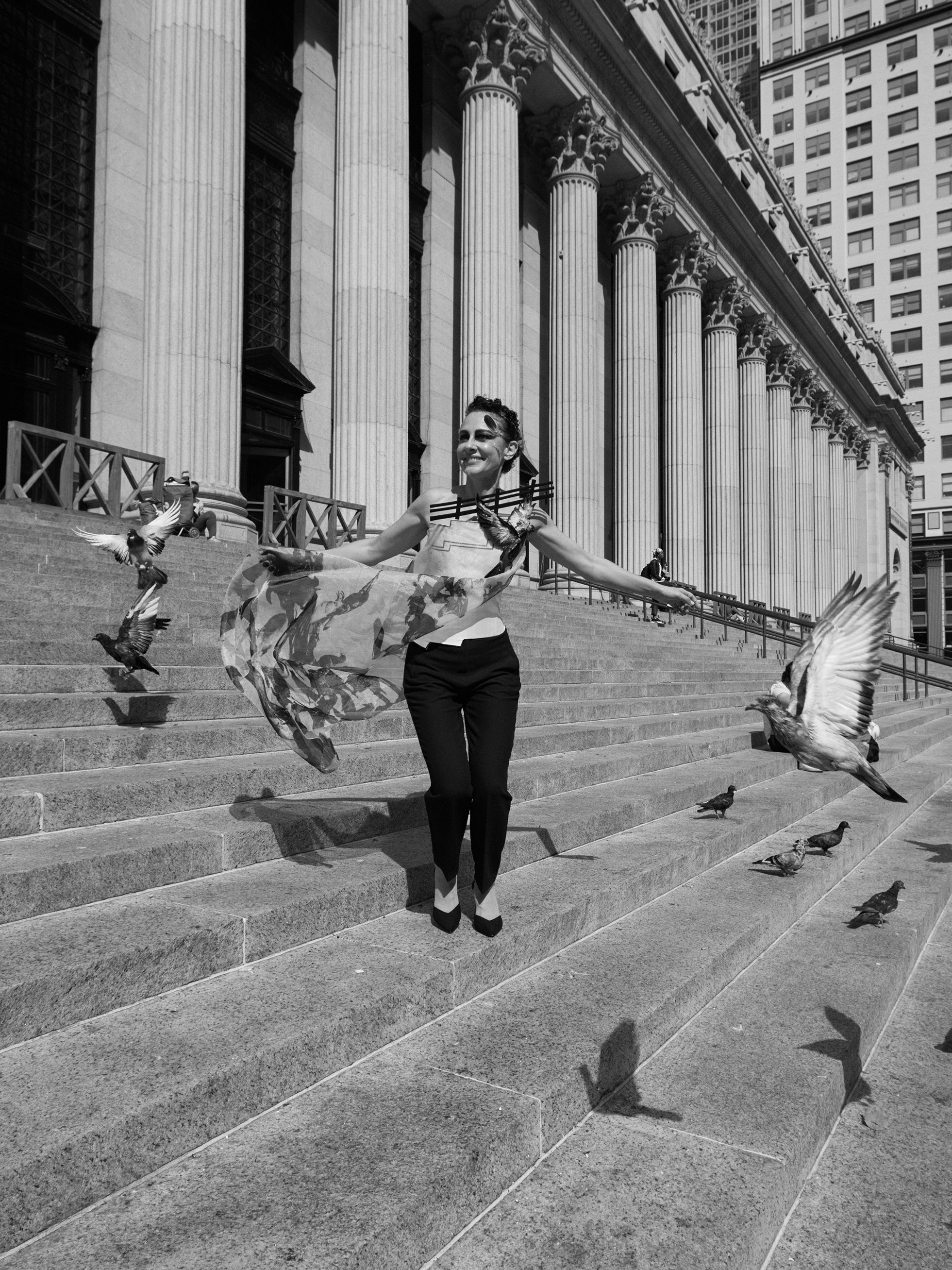 Nicky Conti wearing the Adaptress couture look on the stairs of the James A Farley Building in New York City, moving as pigeons fly past, with a structured corset and printed organza overlay