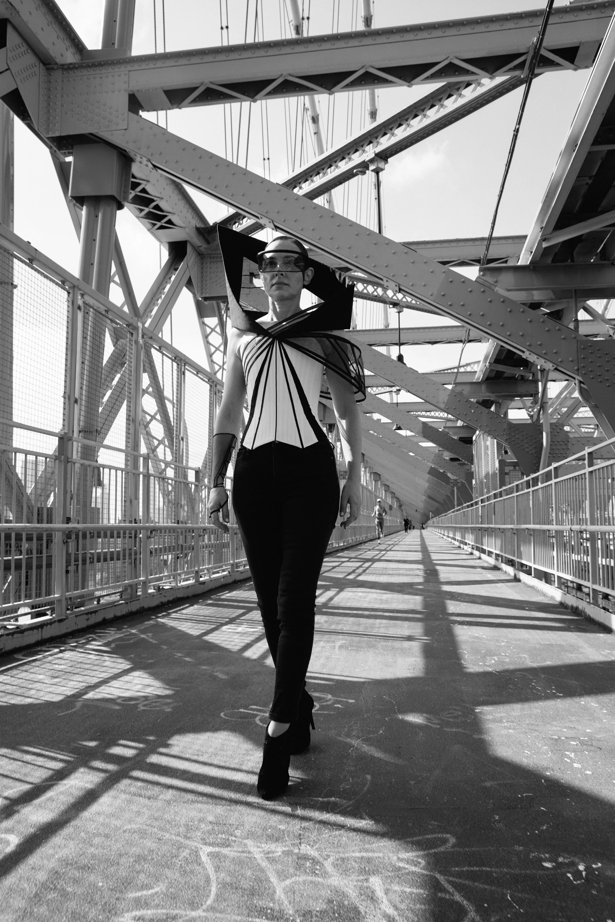 Nicky Conti wearing the Ironick couture look on the Williamsburg Bridge, including a structured corset, mesh arm detail, black dyed jeans, and high-heeled ankle boots