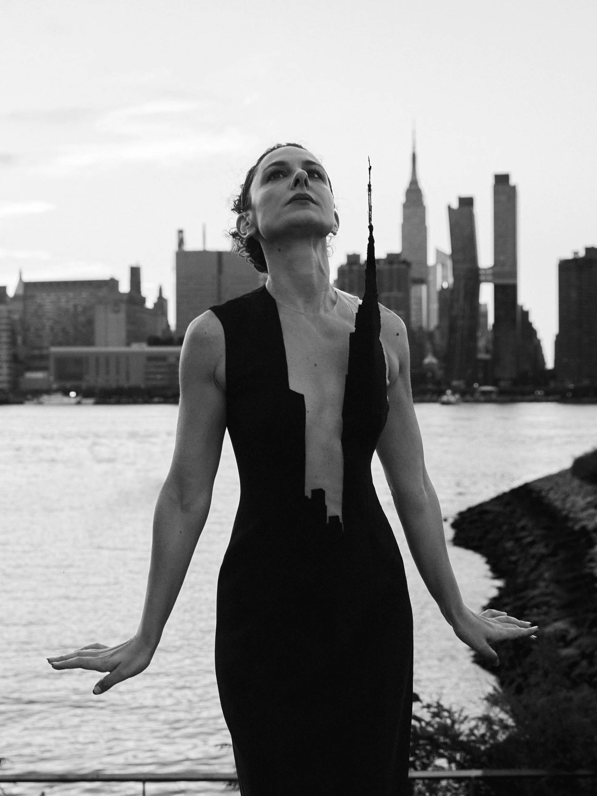 Nicky Conti wearing the Empeiria architectural couture piece with the Empire State Building visible in the Manhattan skyline, photographed from Gantry Plaza Park