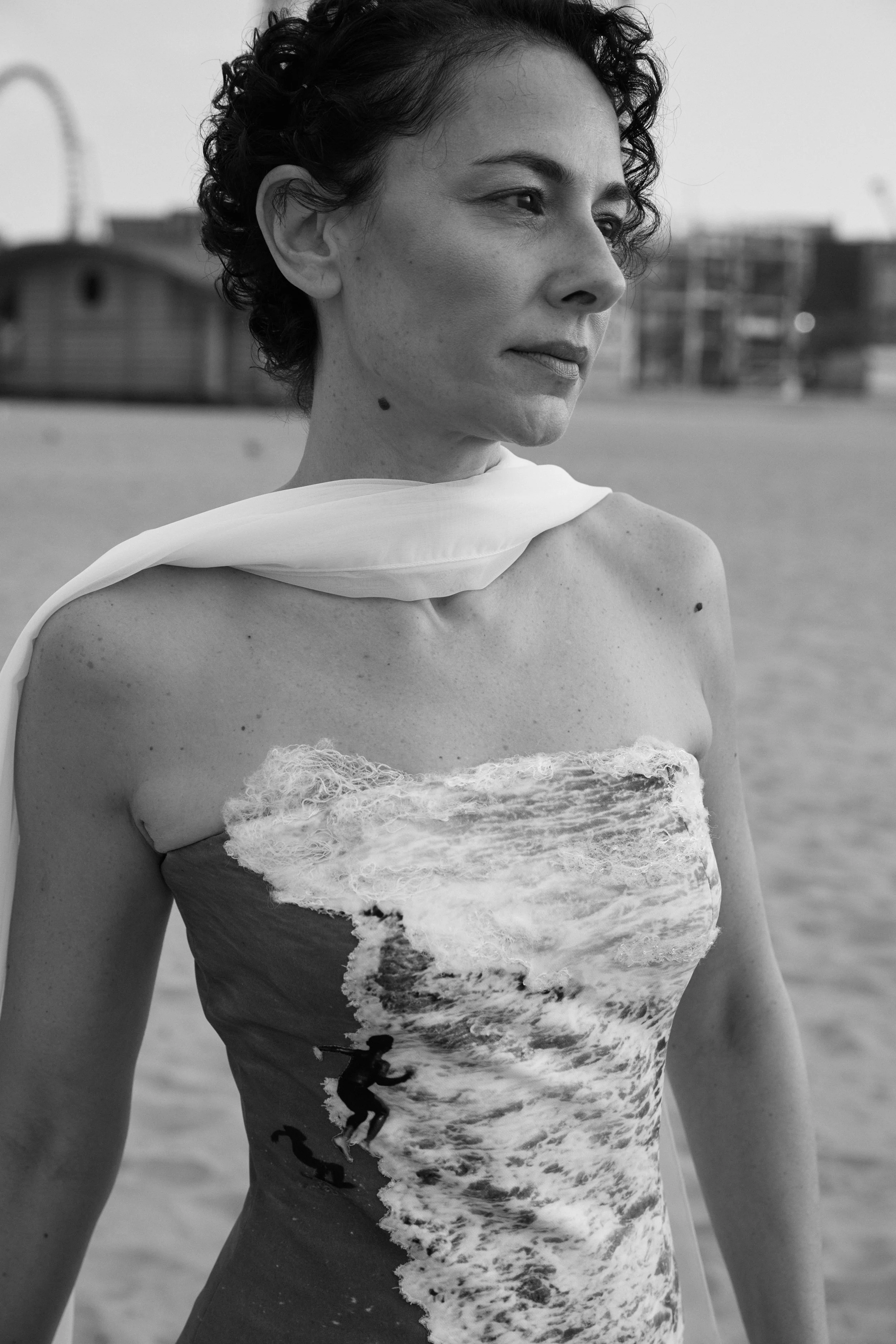 Close-up of Nicky Conti wearing the Memoria couture piece, looking toward the sea on Coney Island Beach