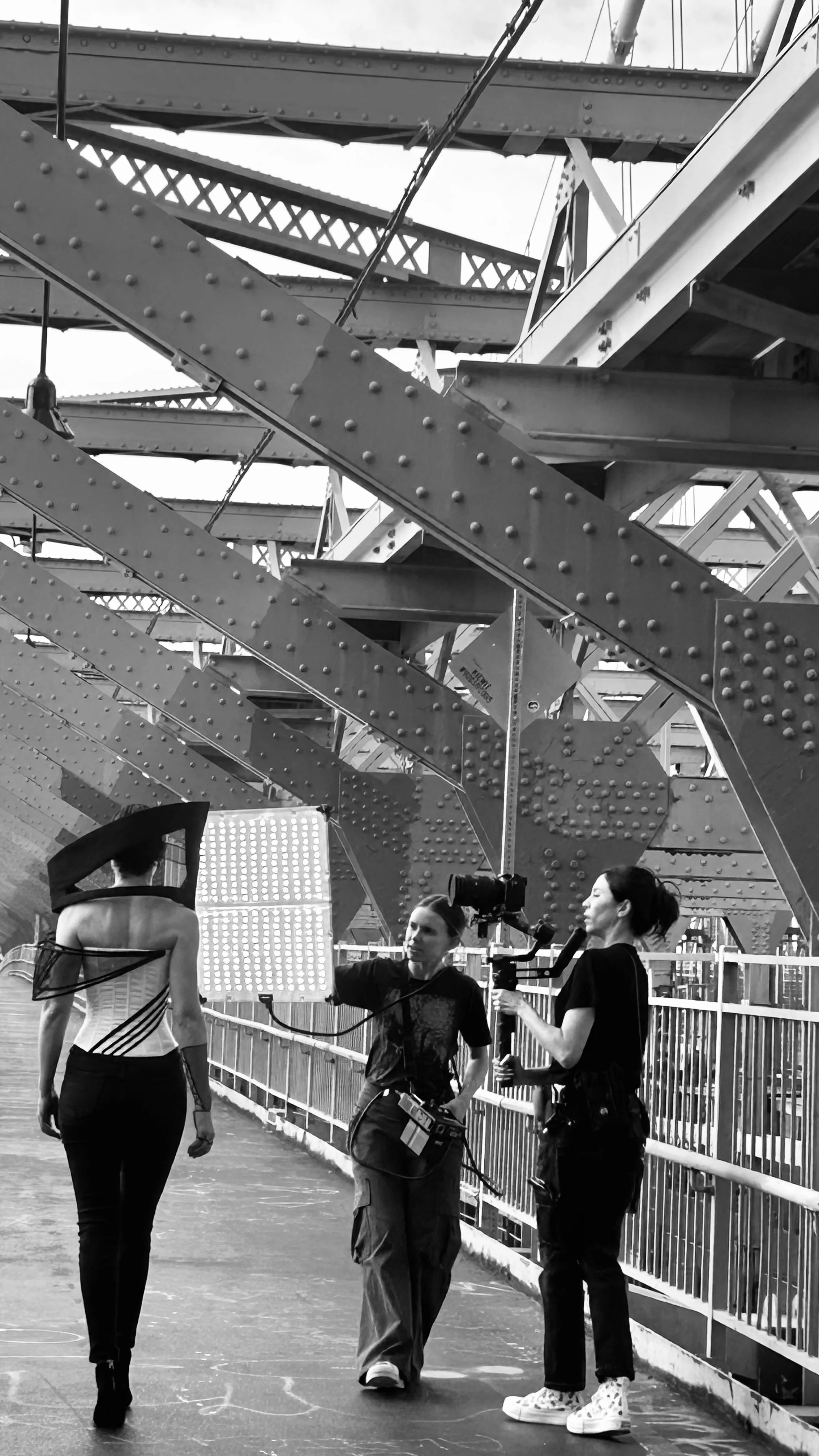 On-location shot of Nicky Conti wearing the Ironick outfit on the Williamsburg Bridge, with photographer Laur Loncar and videographer Emeline Lotherington capturing the final embodiment during the shoot.