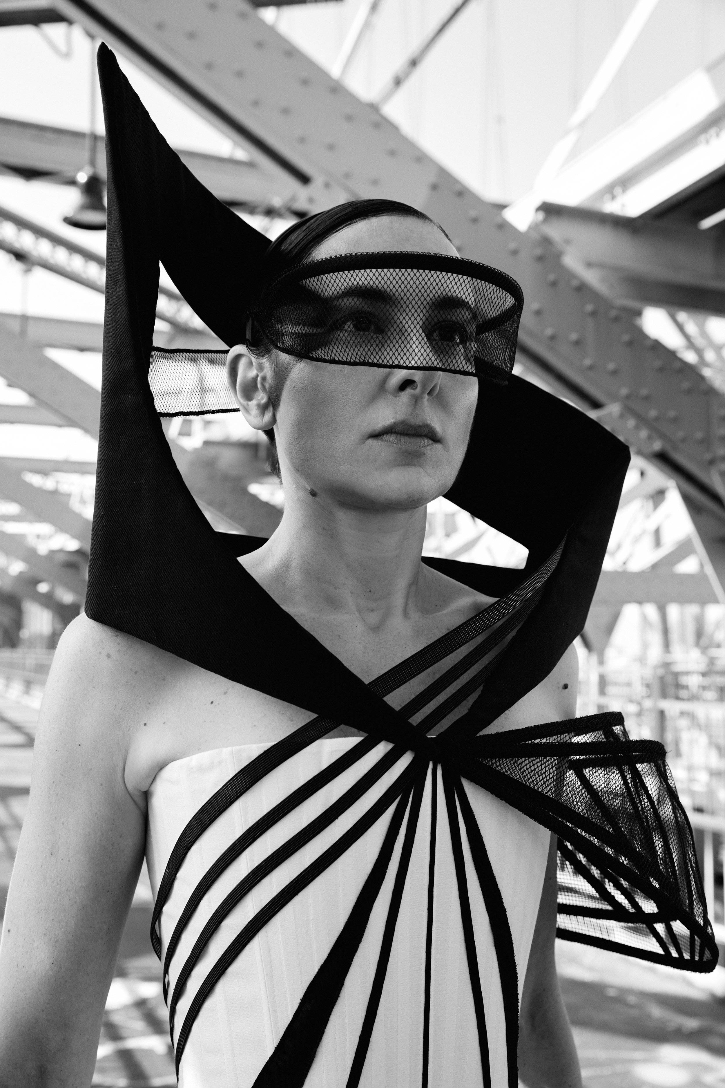 Nicky Conti wearing the Ironick couture piece, close-up showing the structured corset with geometric lines, mesh and boning on one arm, and a sculptural headpiece inspired by the Williamsburg Bridge