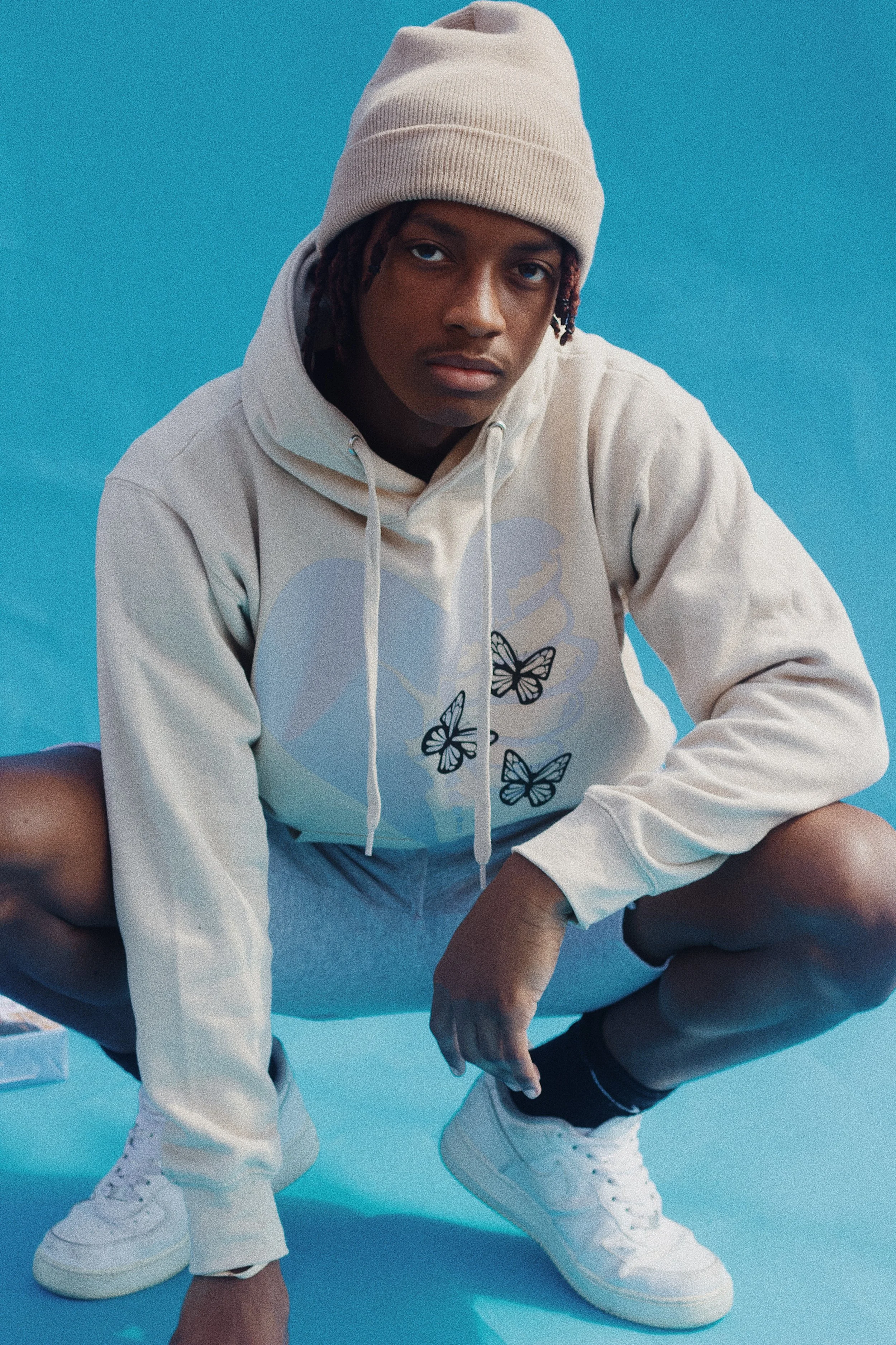 young man wearing urban apparel for a creative studio website with a blue backdrop