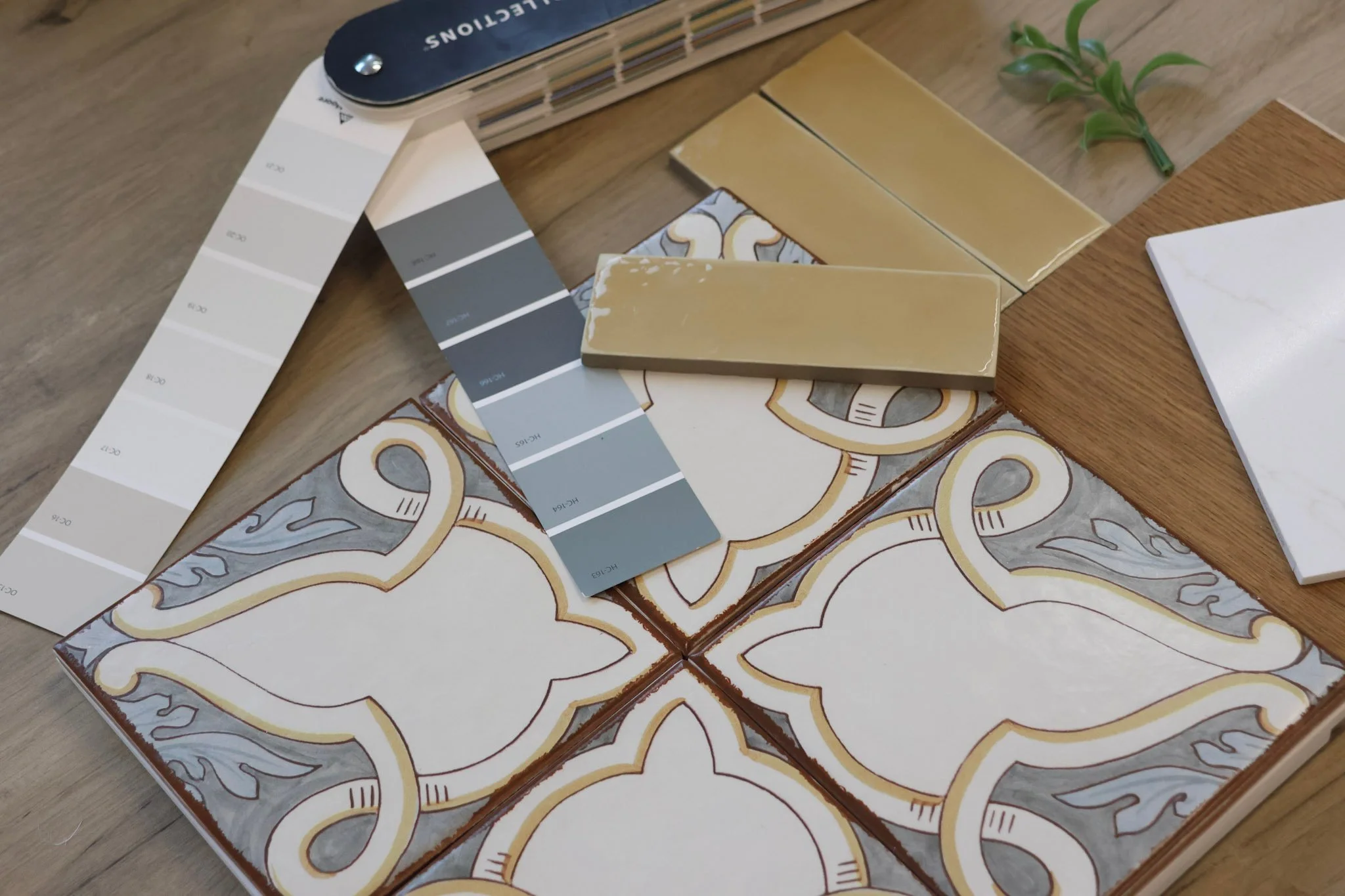 Modern Mediterranean interior design flat lay featuring tile selections, paint samples, wood flooring, and greenery.