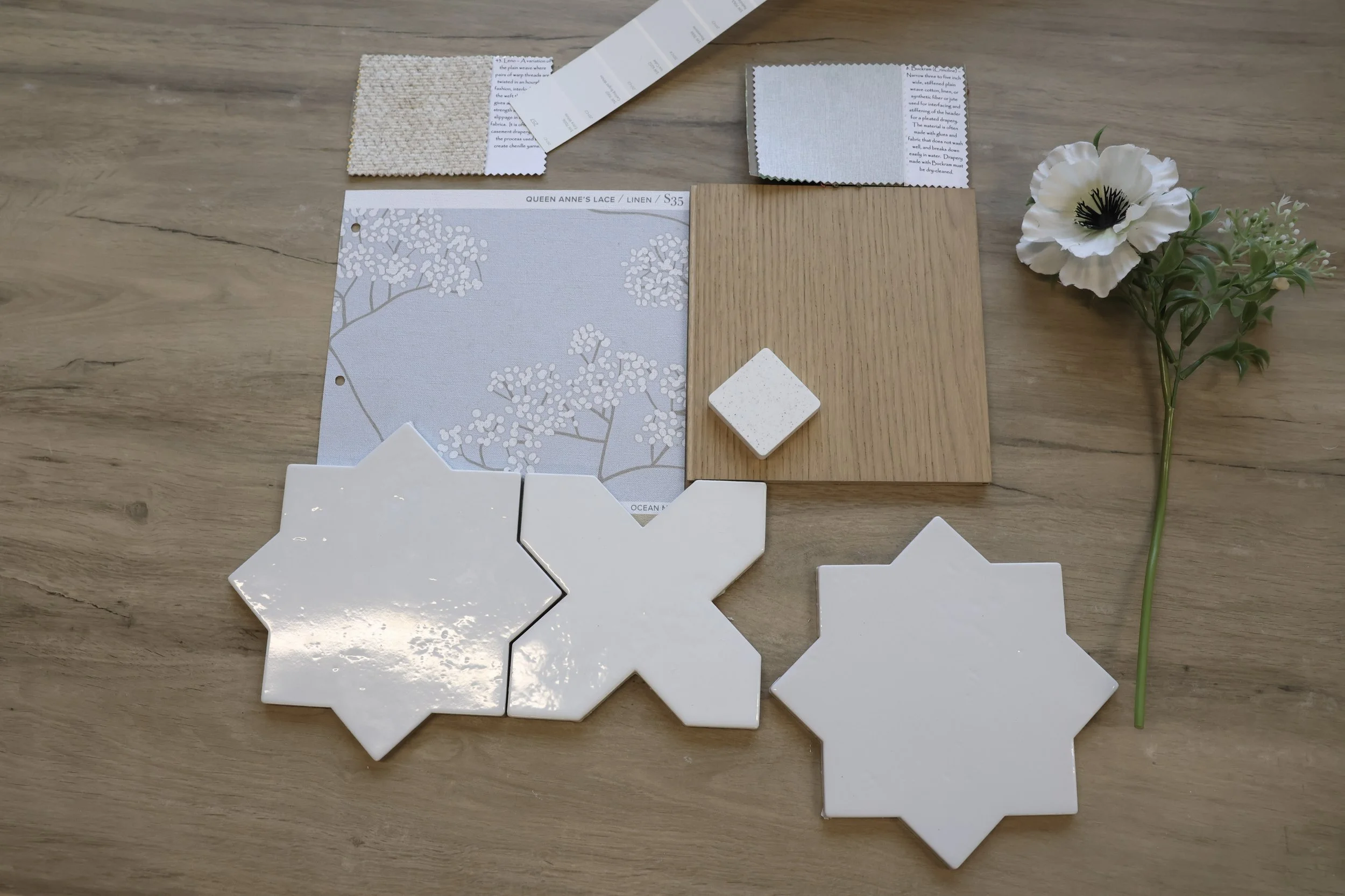 Scandinavian Organic interior design flatlay, includes tile options, paint swatches, wallpaper, wood flooring, and countertop samples, with a white flower on the right side.