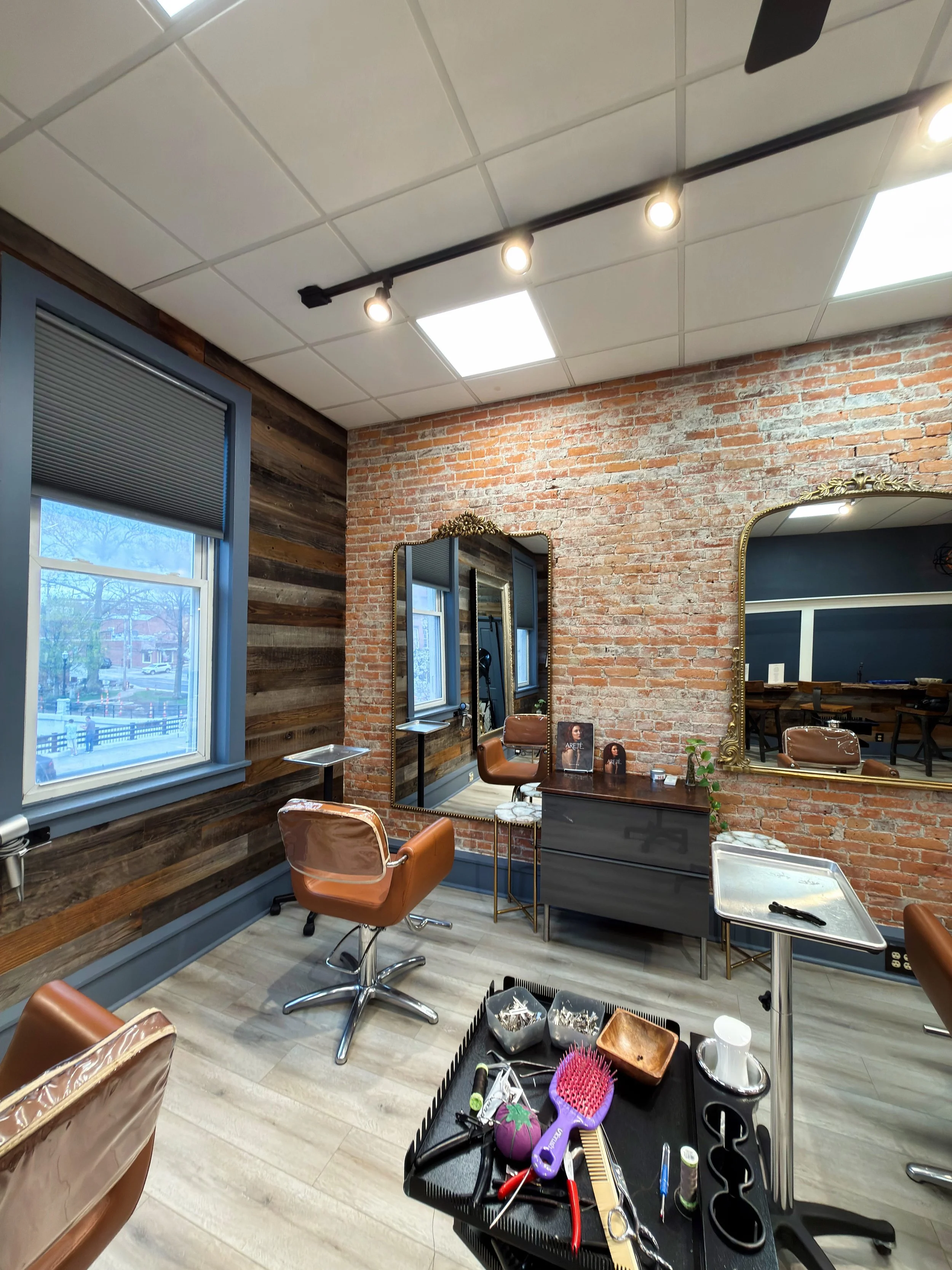Beauty salon or hair studio interior with mirrors, chairs, and hair styling tools on a table.