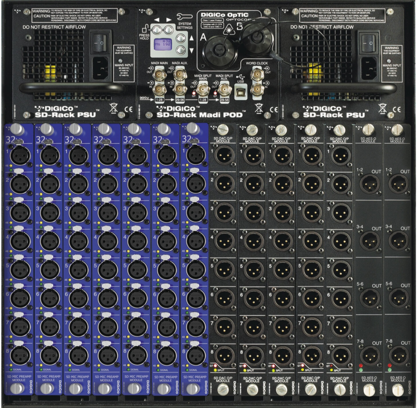 A professional audio mixing console with numerous input and output channels, including analog XLR and digital connectors, knobs, and LED indicators, along with control panels on the top with warnings, system settings, and connection options.