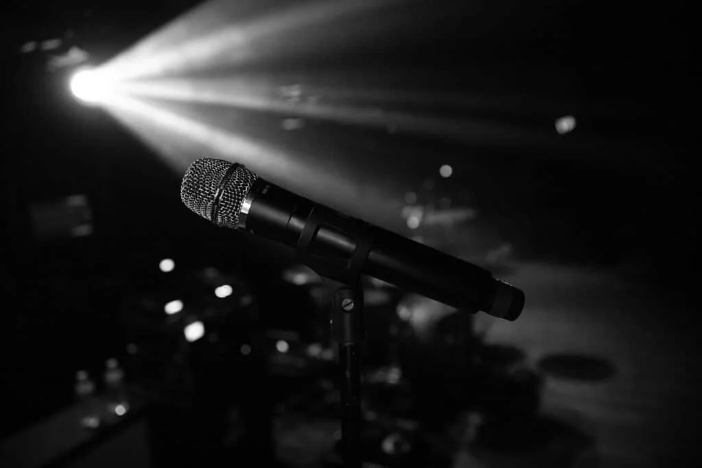 Black microphone on stage with spotlights in background.