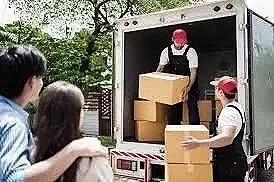 Movers unloading boxes from a truck as neighbors watch.