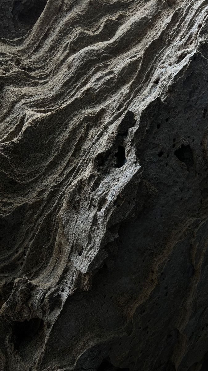 Close-up of a textured, porous rock formation with layered, jagged patterns and holes.