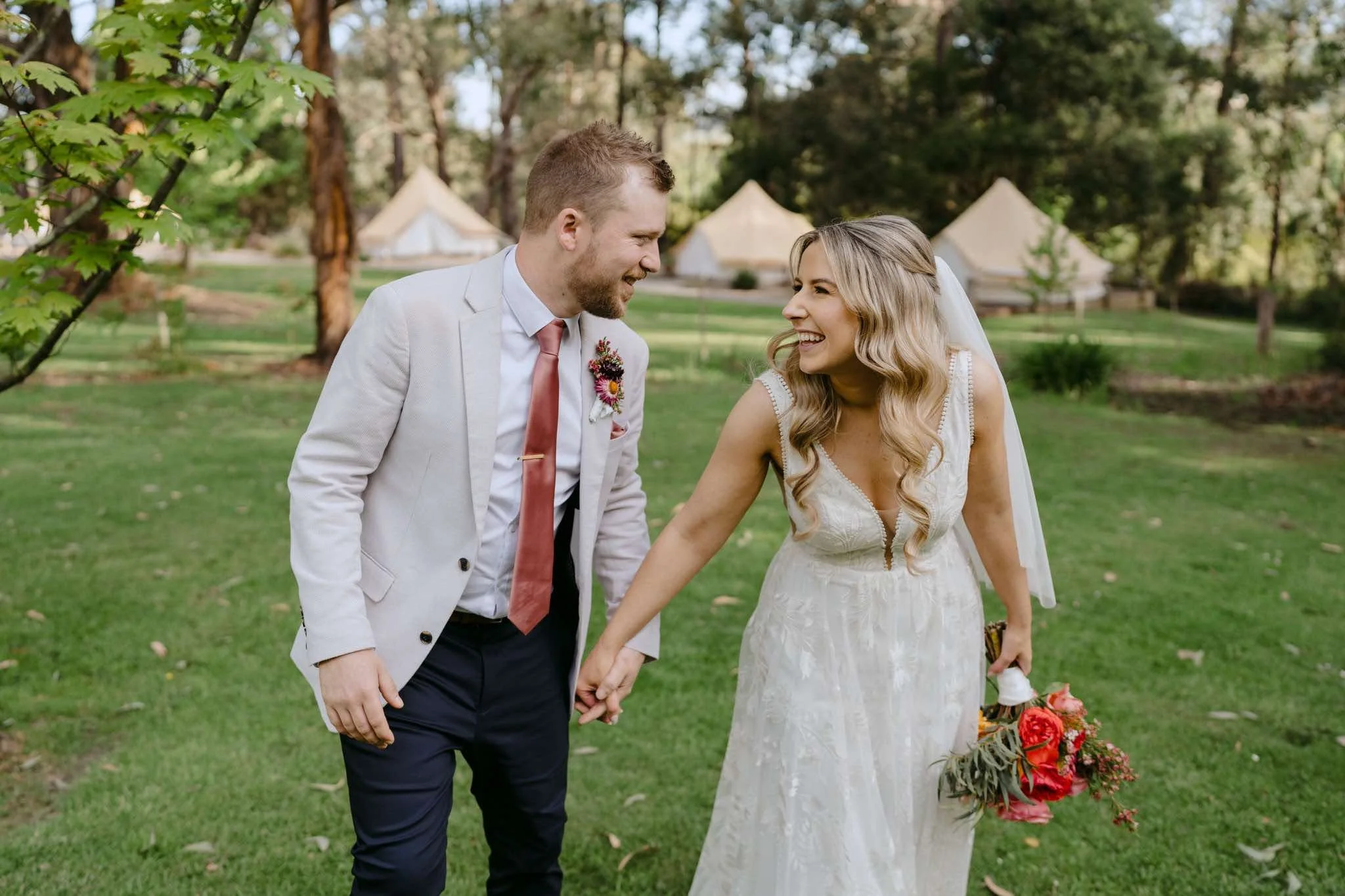 Newlywed couple holding hands outdoors on their wedding day, bride wearing a lace wedding gown after expert bridal alterations in Melbourne