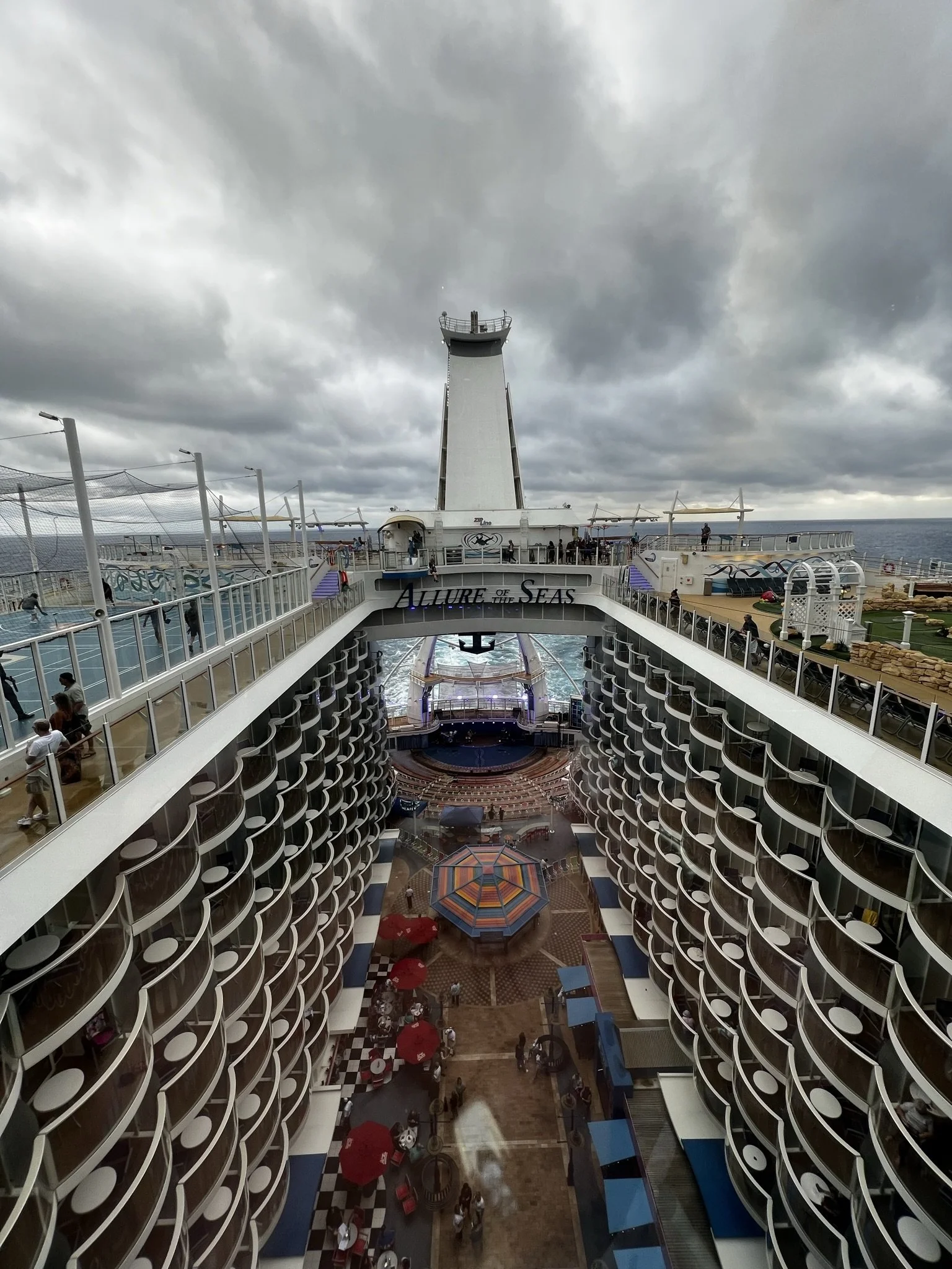 Aerial view of a cruise ship's balcony staterooms and open deck near a lighthouse
