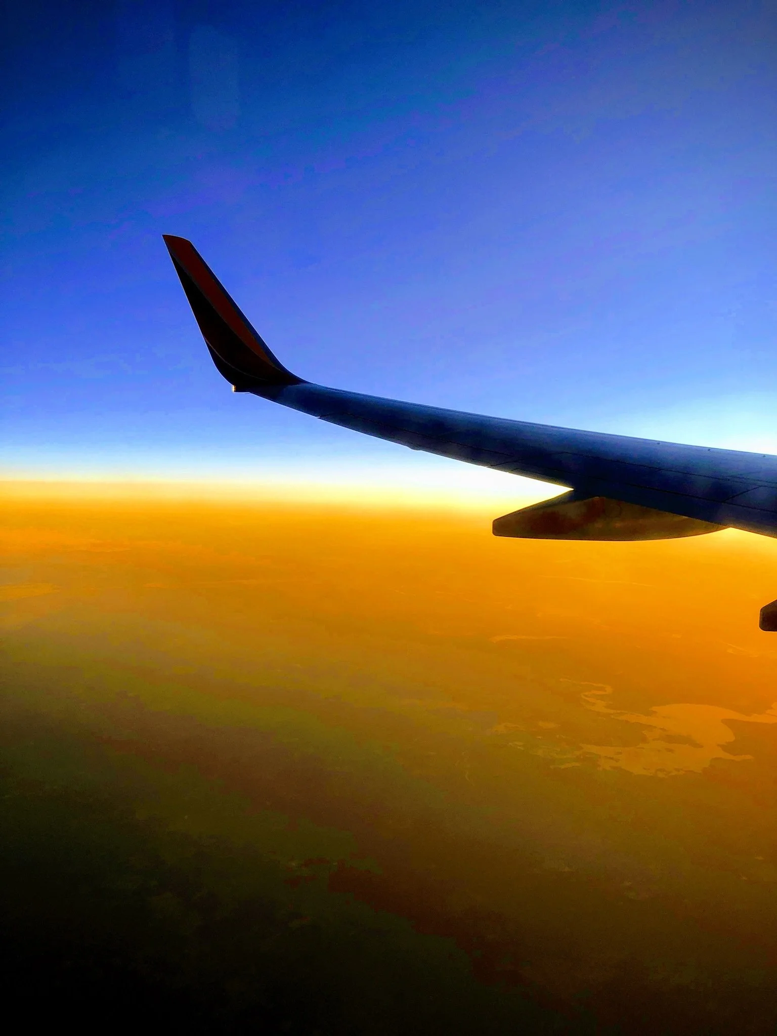 Airplane wing over clouds at sunset, symbolizing flight booking timing around Black Friday