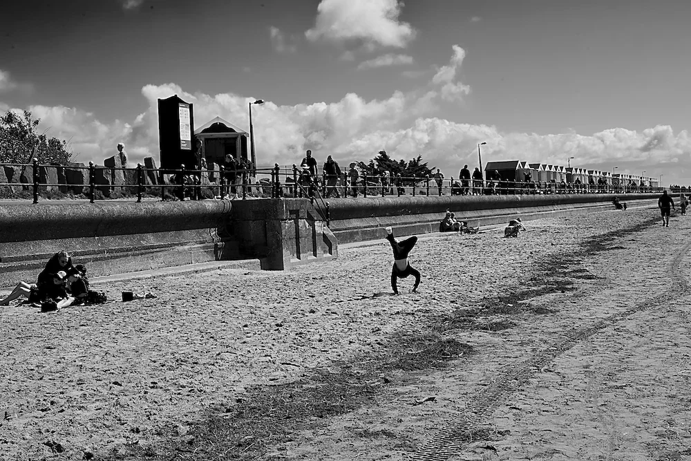 northwest-coast-handstand-beach-huts-sea-wall-lancashire-bw.webp