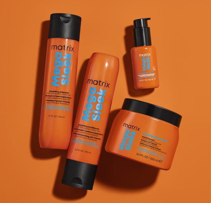 A set of orange hair care products from the Matrix Mega Sleek line, including shampoo, conditioner, a small bottle, and a large jar on an orange background.