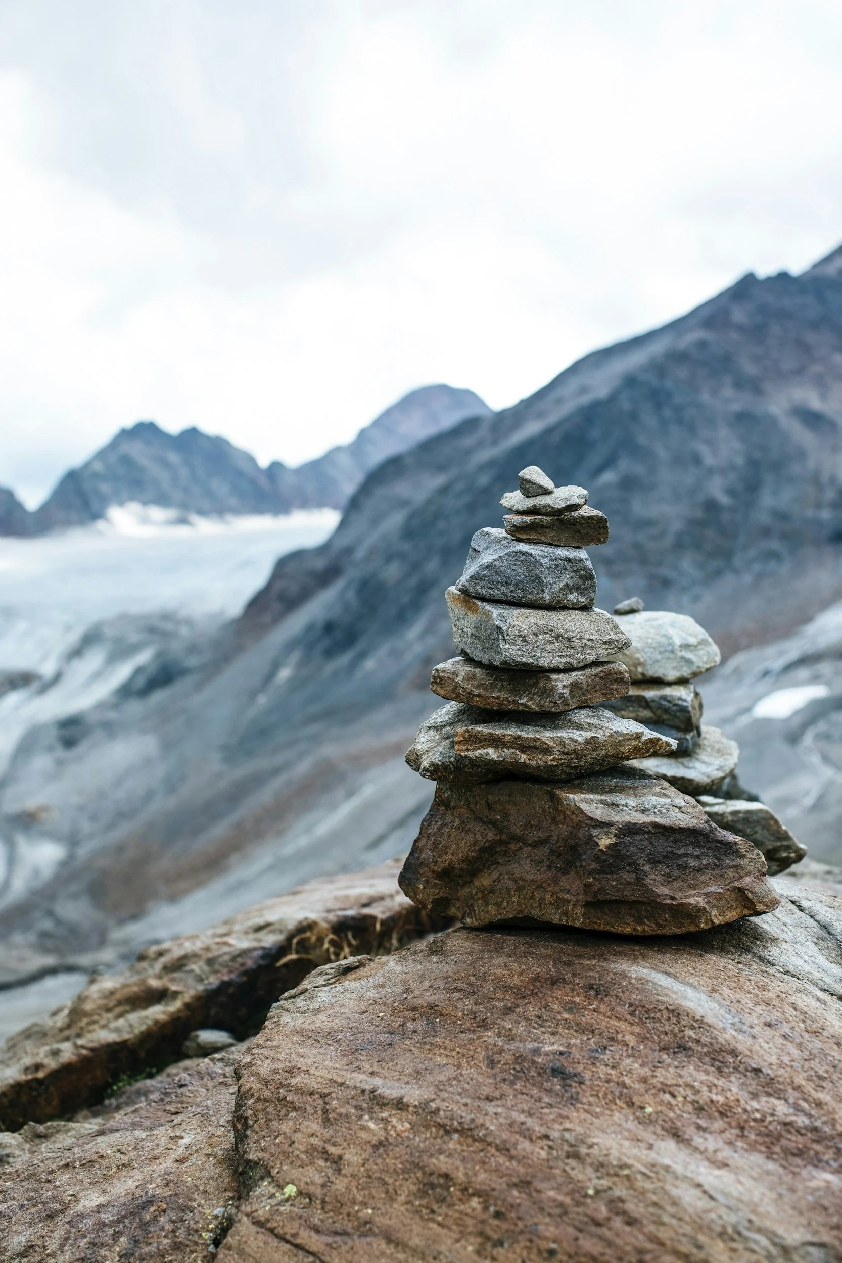 Stacked rocks on a rocky surface with mountain landscape in background.