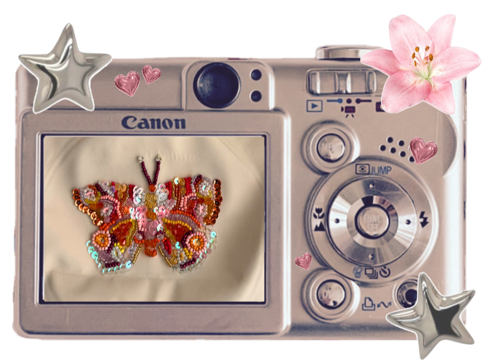 A digital camera with a butterfly embroidered patch inside the screen, decorated with pink hearts, stars, and a pink flower around it.