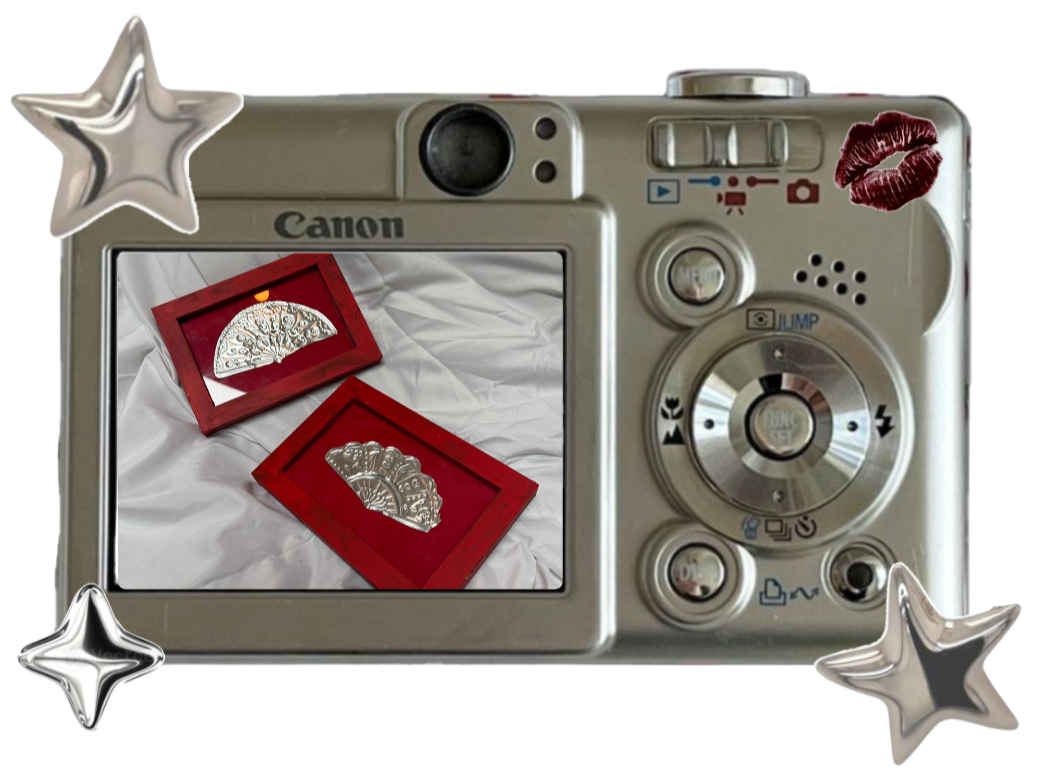 A camera screen shows two decorative silver fans in red frames, placed on white fabric, with star and lip stickers around the camera.
