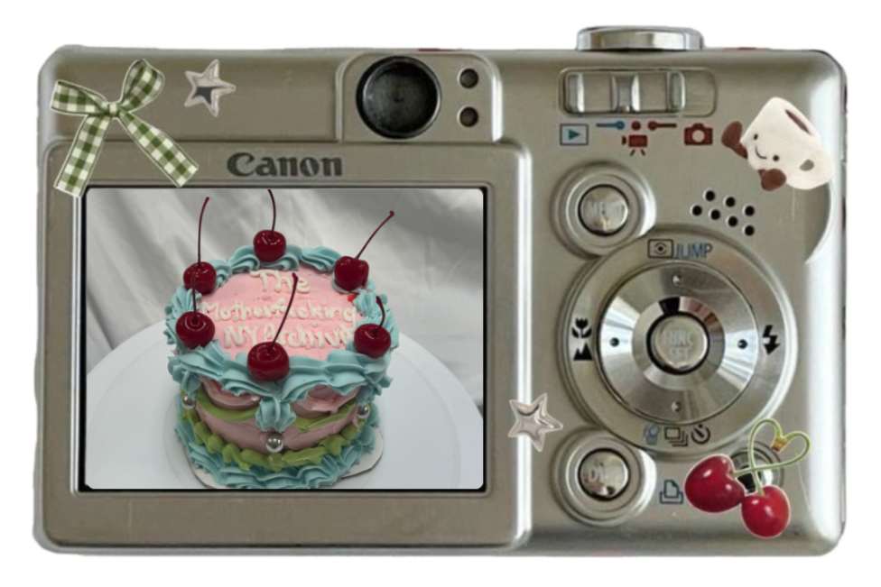 A digital camera decorated with stickers of a bow, stars, a dog, and cherries, displaying a picture of a colorful layered cake with cherries on top and birthday message.