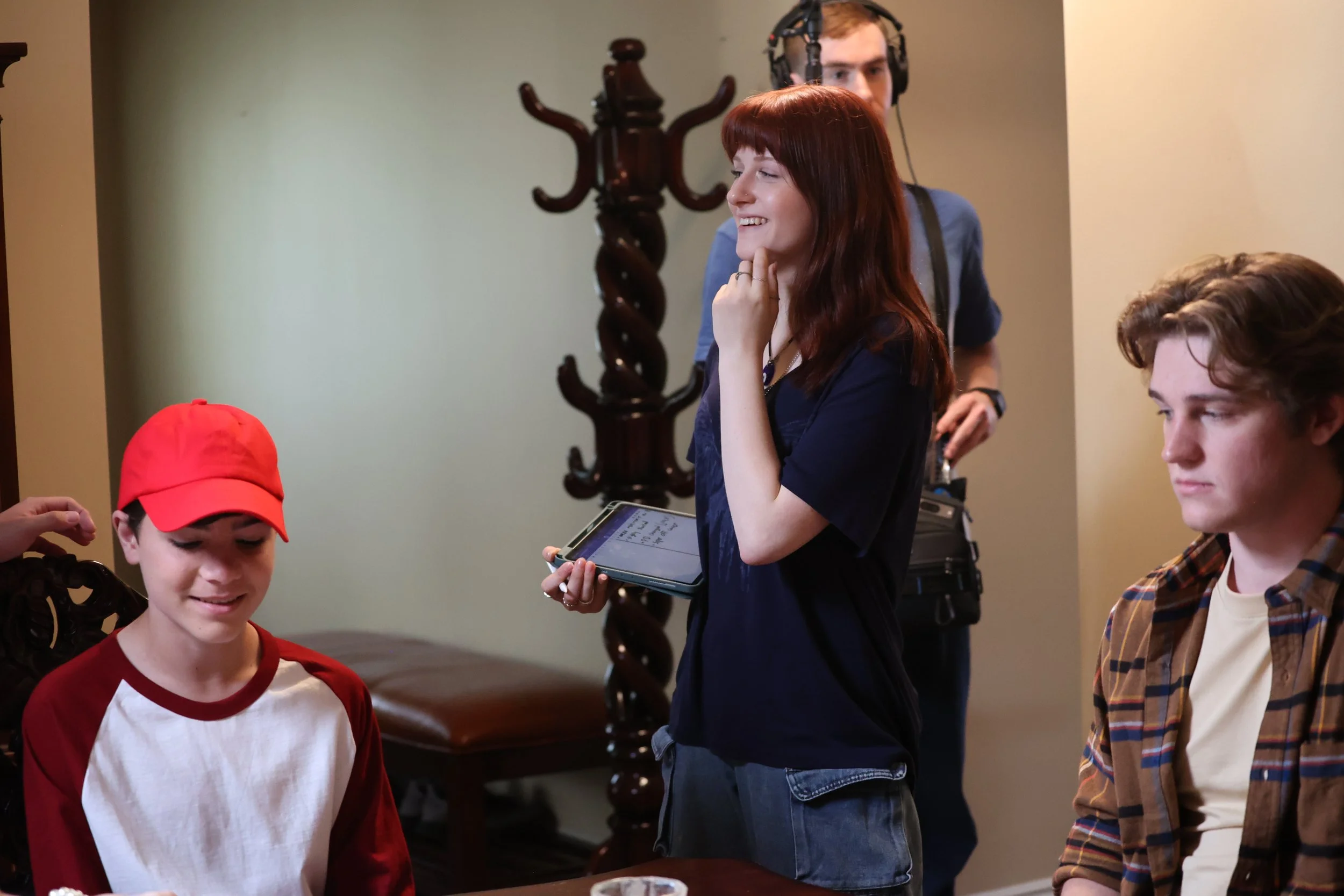 Group of young people on a film set with a director, two actors, and a behind-the-scenes crew member, preparing for a scene.