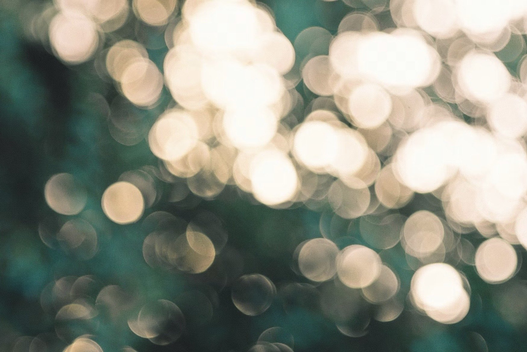 Blurred lights creating a bokeh effect with soft, circular shapes in shades of cream, white, and teal.