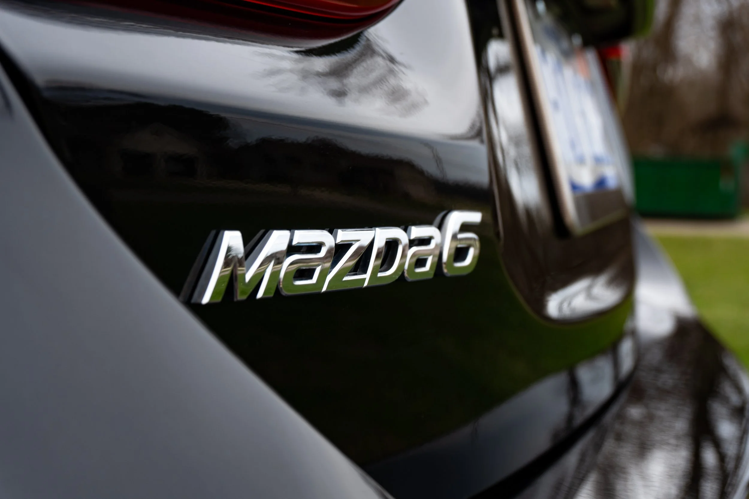 Close-up of a black Mazda6 car with a silver emblem.