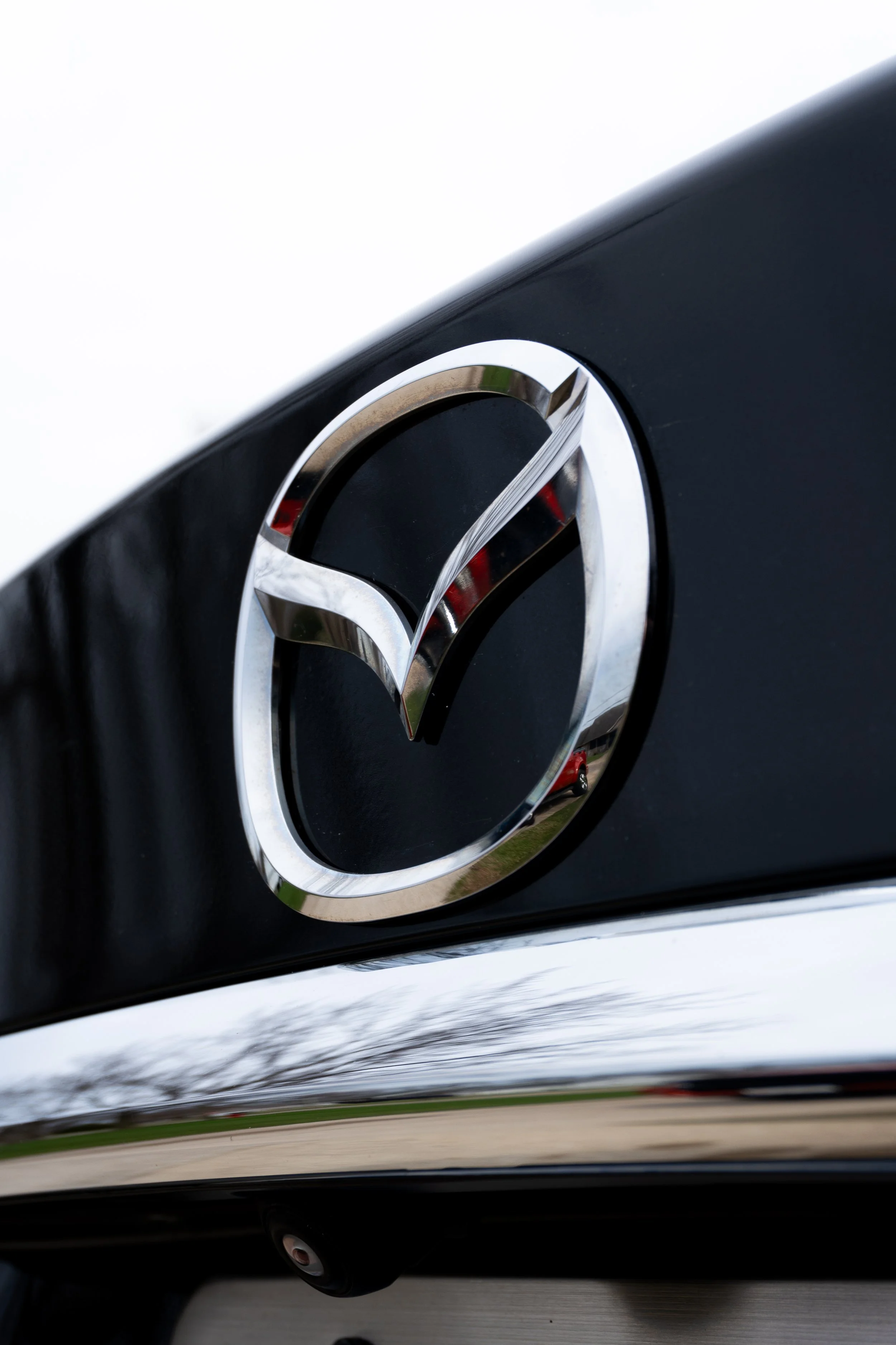 Close-up of the Mazda logo on the front grill of a car.
