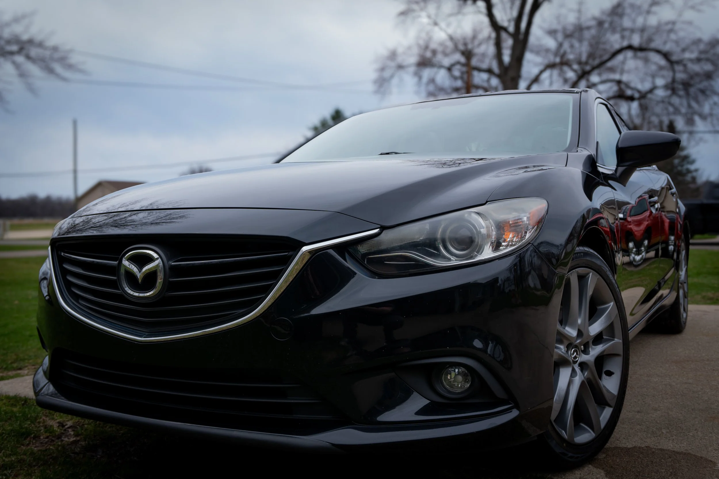 Black Mazda sedan parked outdoors on a driveway.