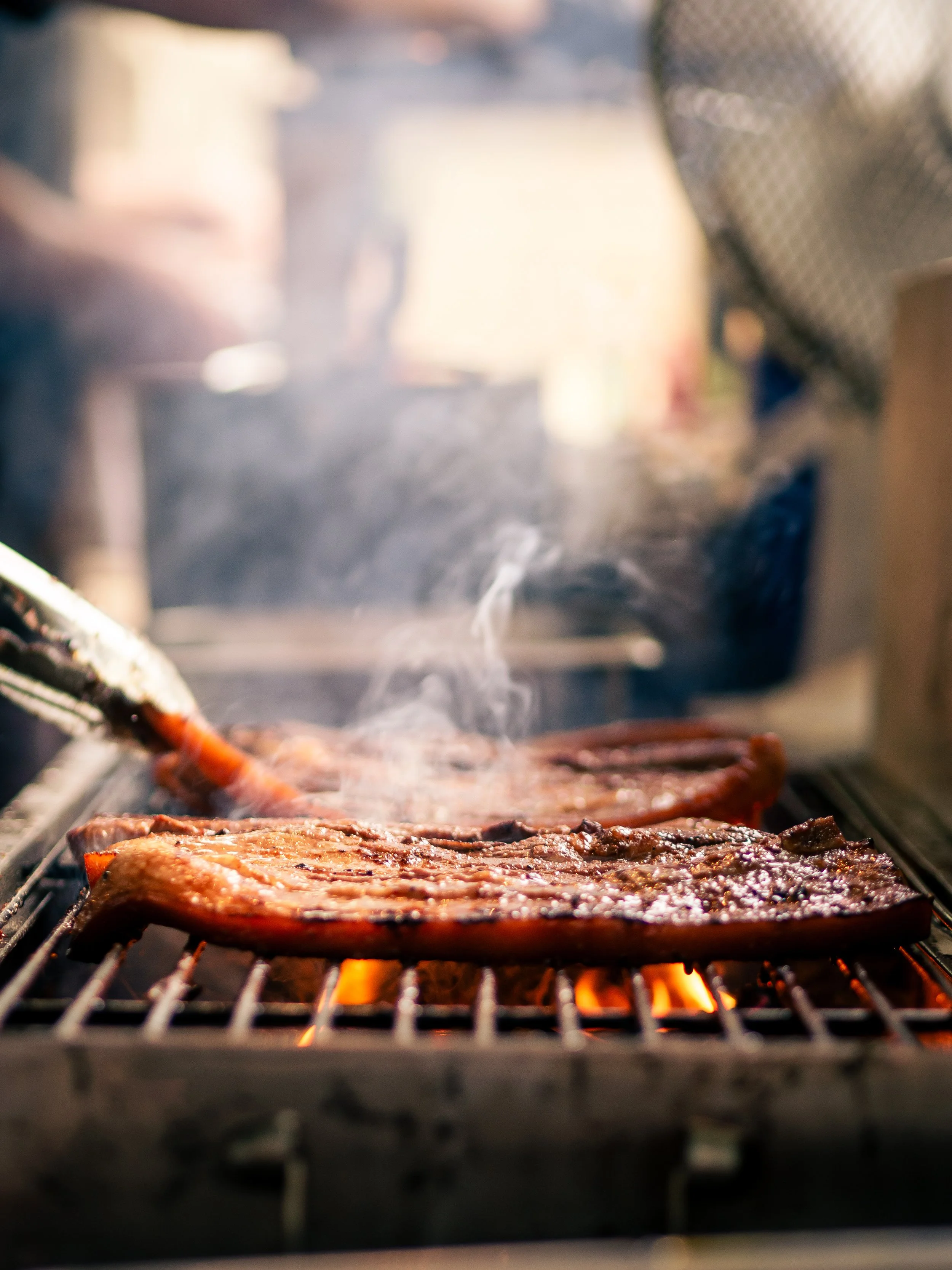 Steak cooking on a grill over open flame.